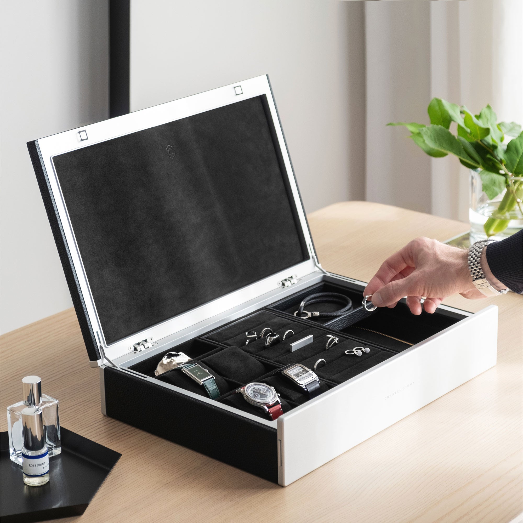 Lifestyle photo of man putting ring in his Taylor 4 Watch and Jewelry box in black leather displaying his entire watch and jewelry collection in his home.