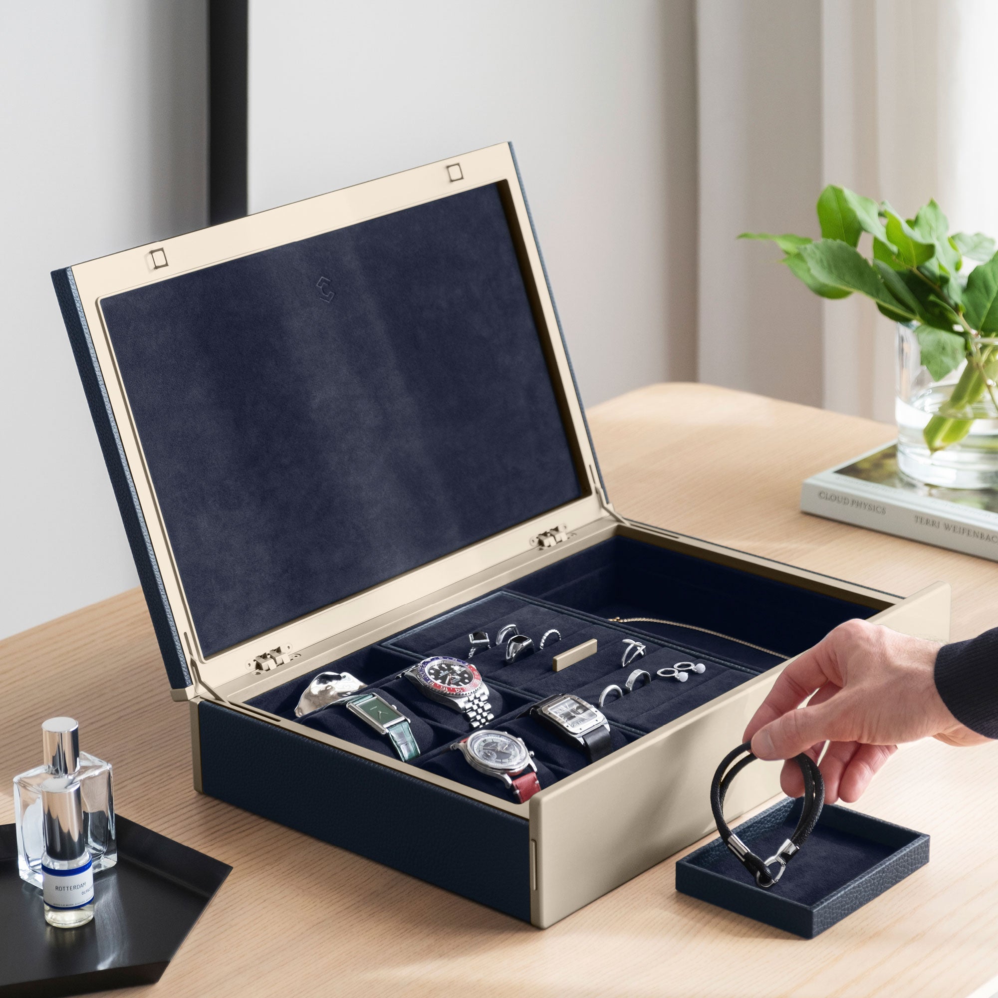 Man taking bracelet from removable jewelry organization tray. The marine Taylor 4 is also storing 4 luxury timepieces as well as multiple rings and necklaces.