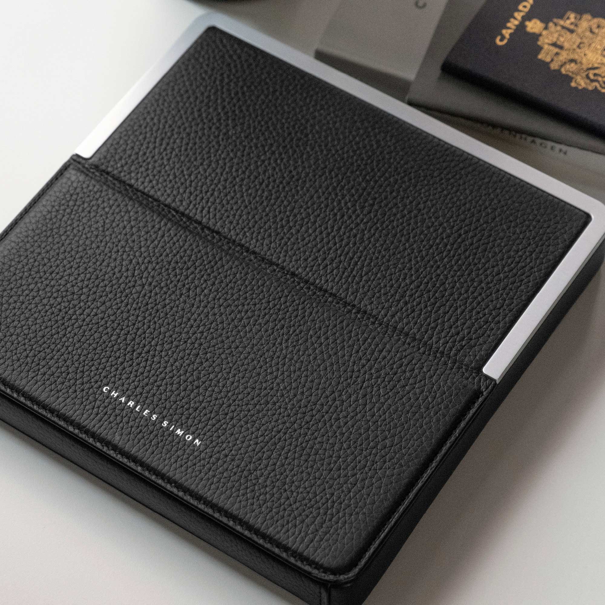 Lifestyle photo showcasing the black leather and grey aluminum premium materials and sleek, elegant design of the Fraser Travel wallet