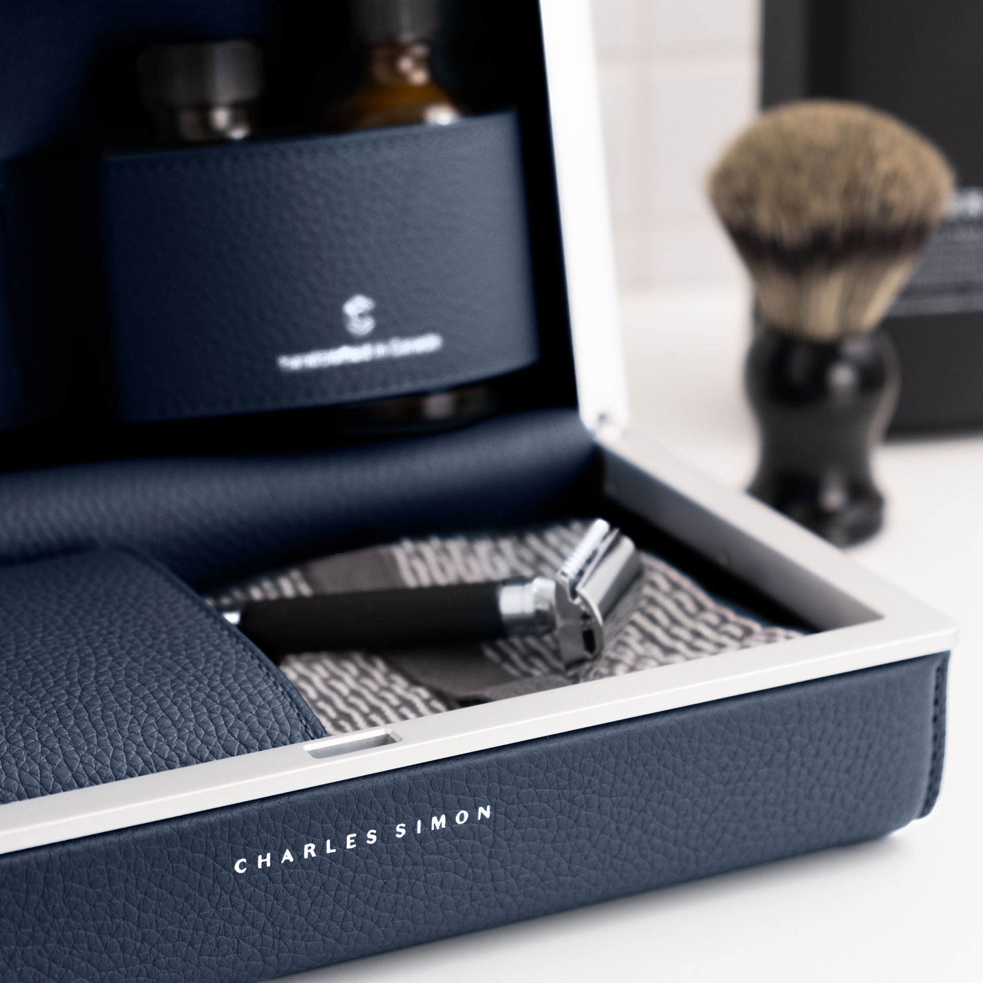 Lifestyle photo of open marine leather toiletry bag by Charles Simon holding razor and skincare essentials