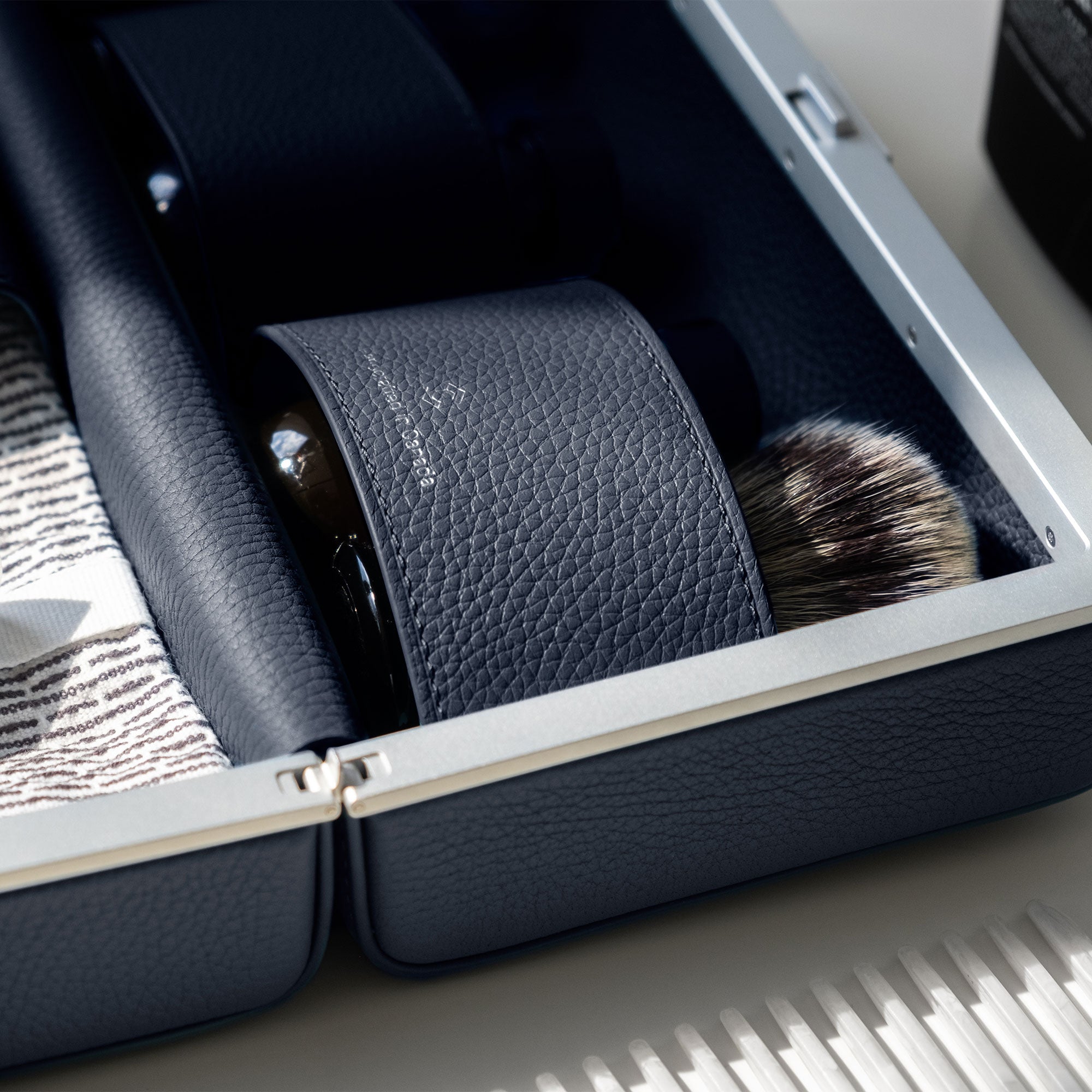 Detail photo of marine leather Moraine Toiletry bag holding makeup brush