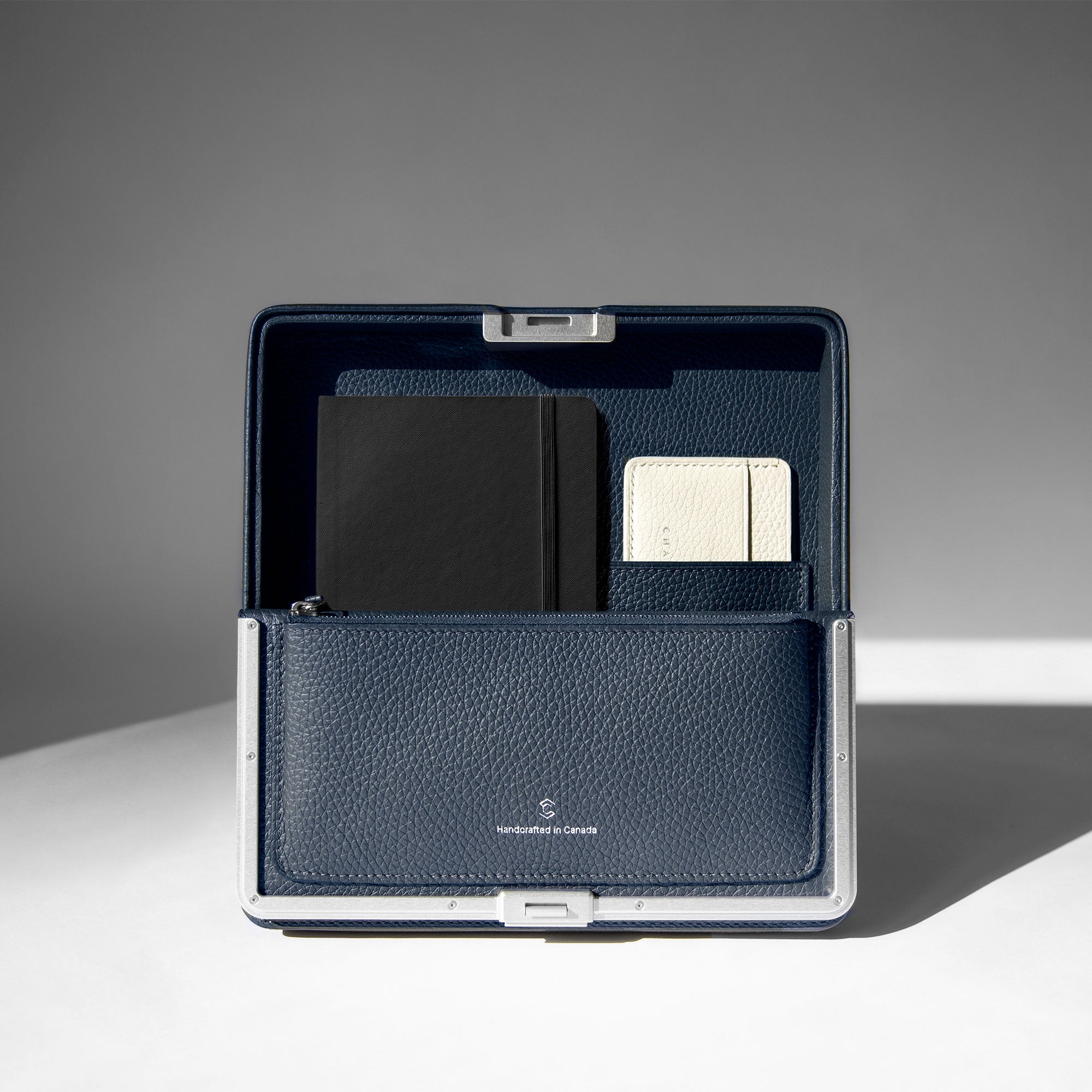 Lifestyle photo of open Fraser Travel wallet holding a notebook and card holder. Handmade in Canada.