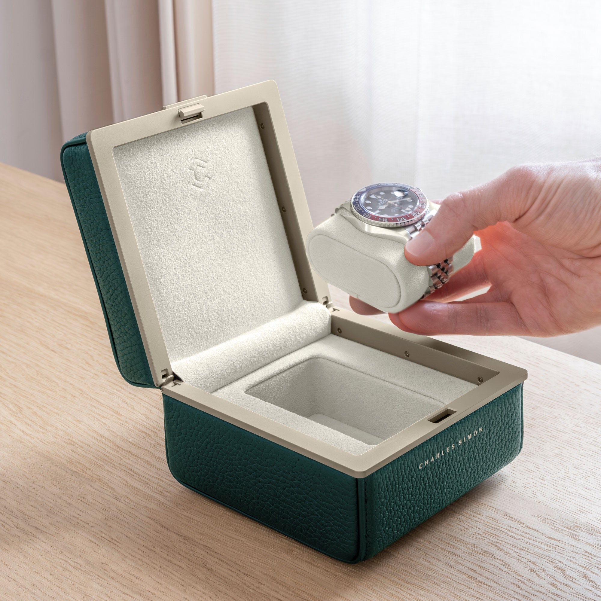 Man taking his Rolex luxury watch from the Eaton 1 Watch case in gold and emerald leather and eggshell Alcantara interior