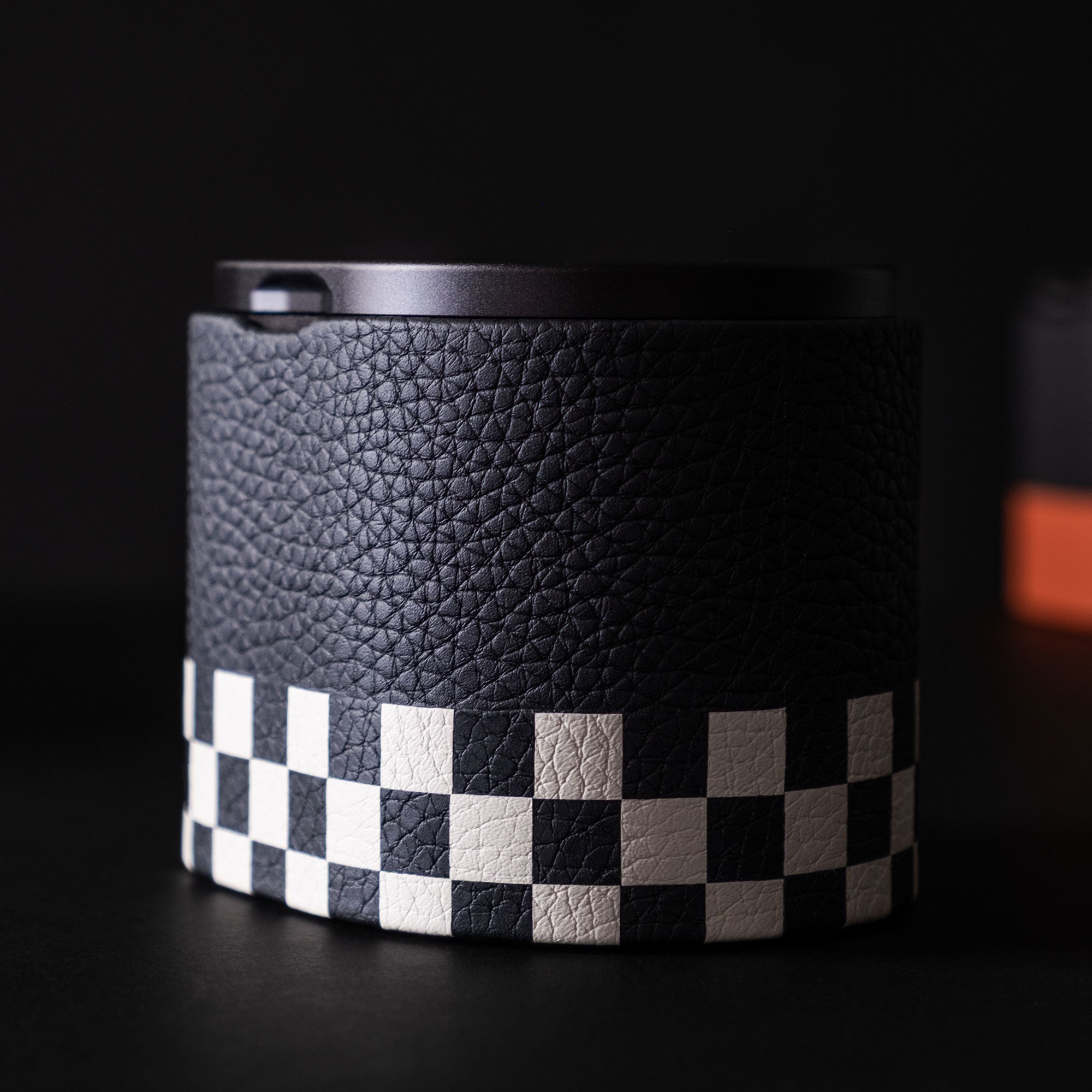 Product photo showcasing the marquetry on the black and white leather watch roll by Charles Simon in front of a dark background. Designed to store, transport and display one timepiece. 