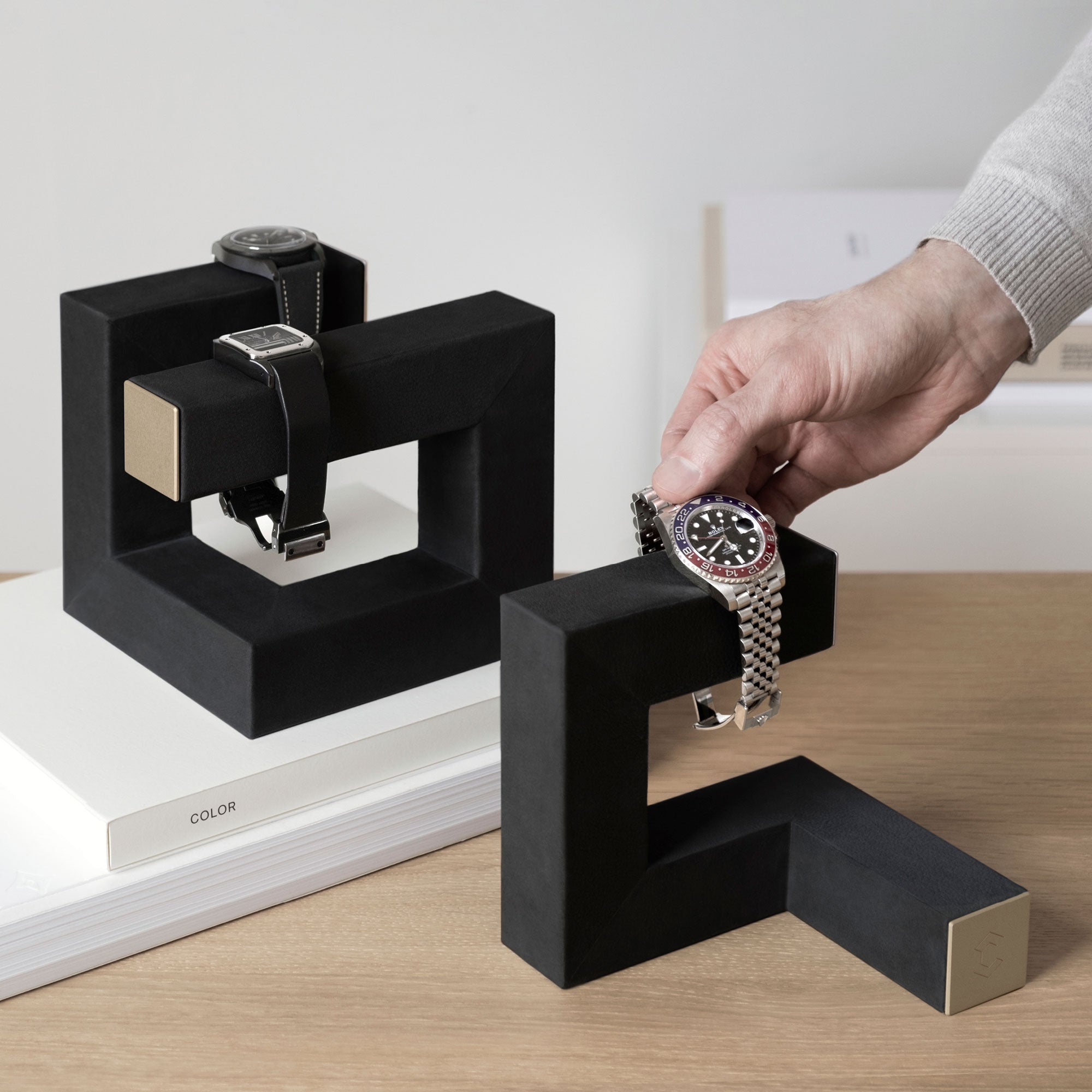 Hudson Watch stands in black leather and gold displaying watches at home. Man is taking his watch from the watch stand 