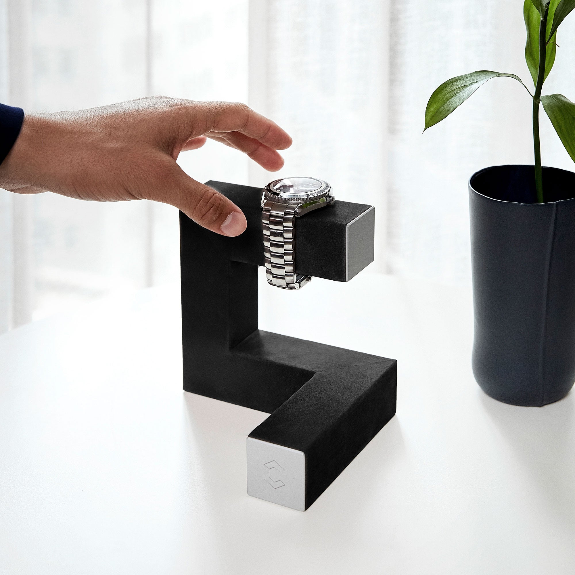 Lifestyle shot of minimalist sculptural Hudson watch stand inspired by modern art holding luxury timepiece