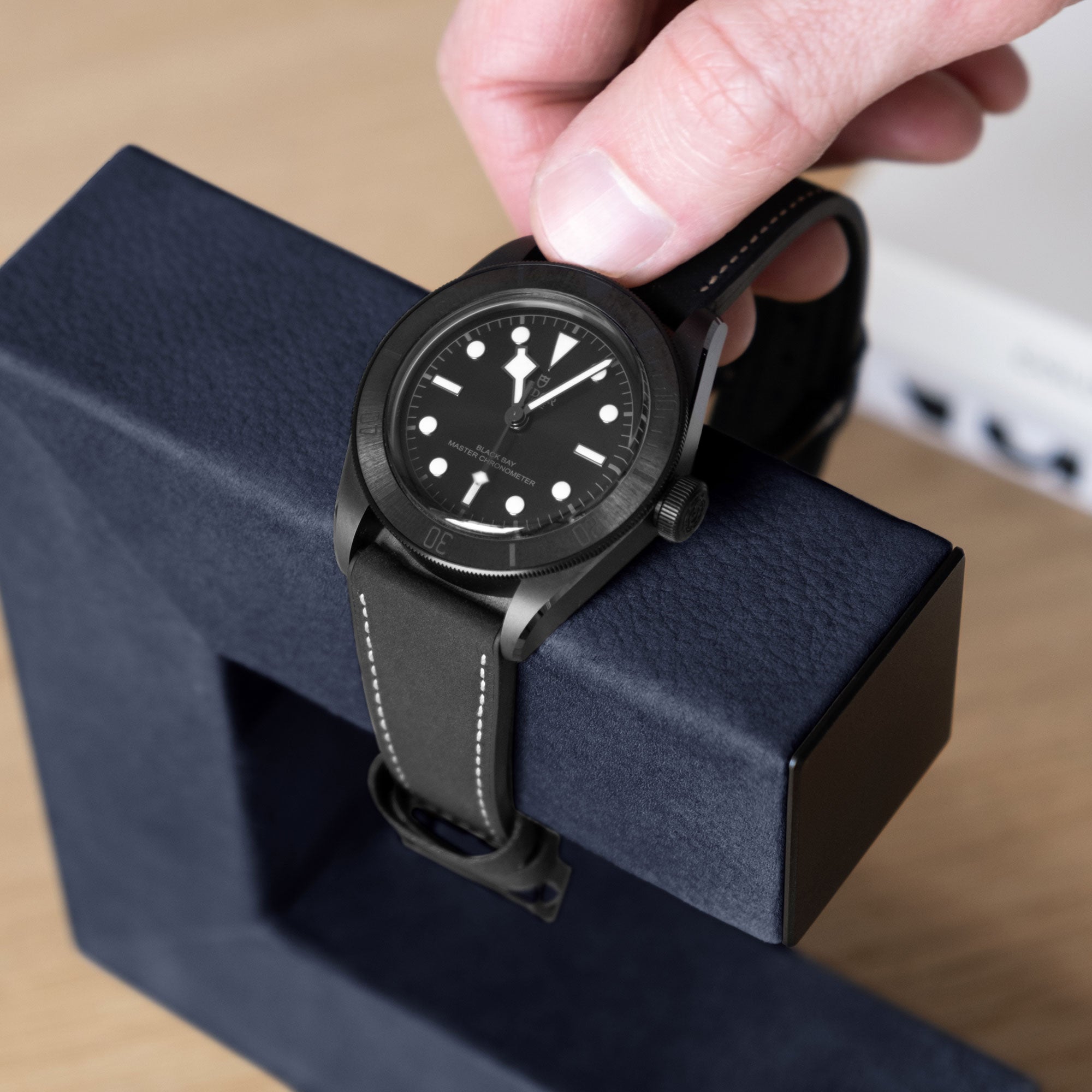 Luxury watch being taken from designer watch stand in navy nubuck leather