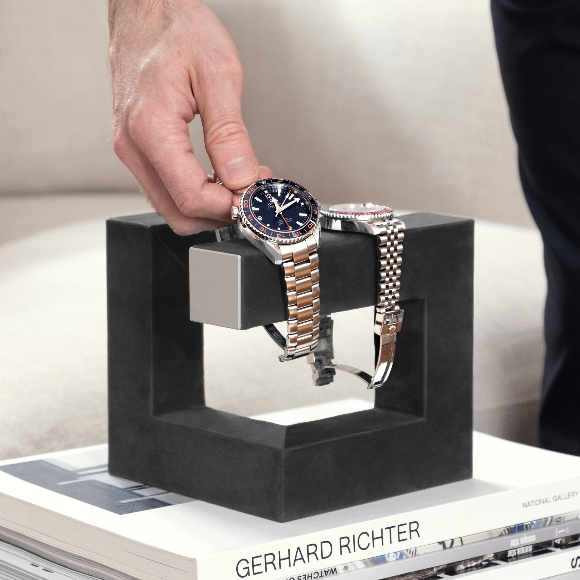 Man taking his Omega luxury watch from the Hudson 3 Watch stand in grey