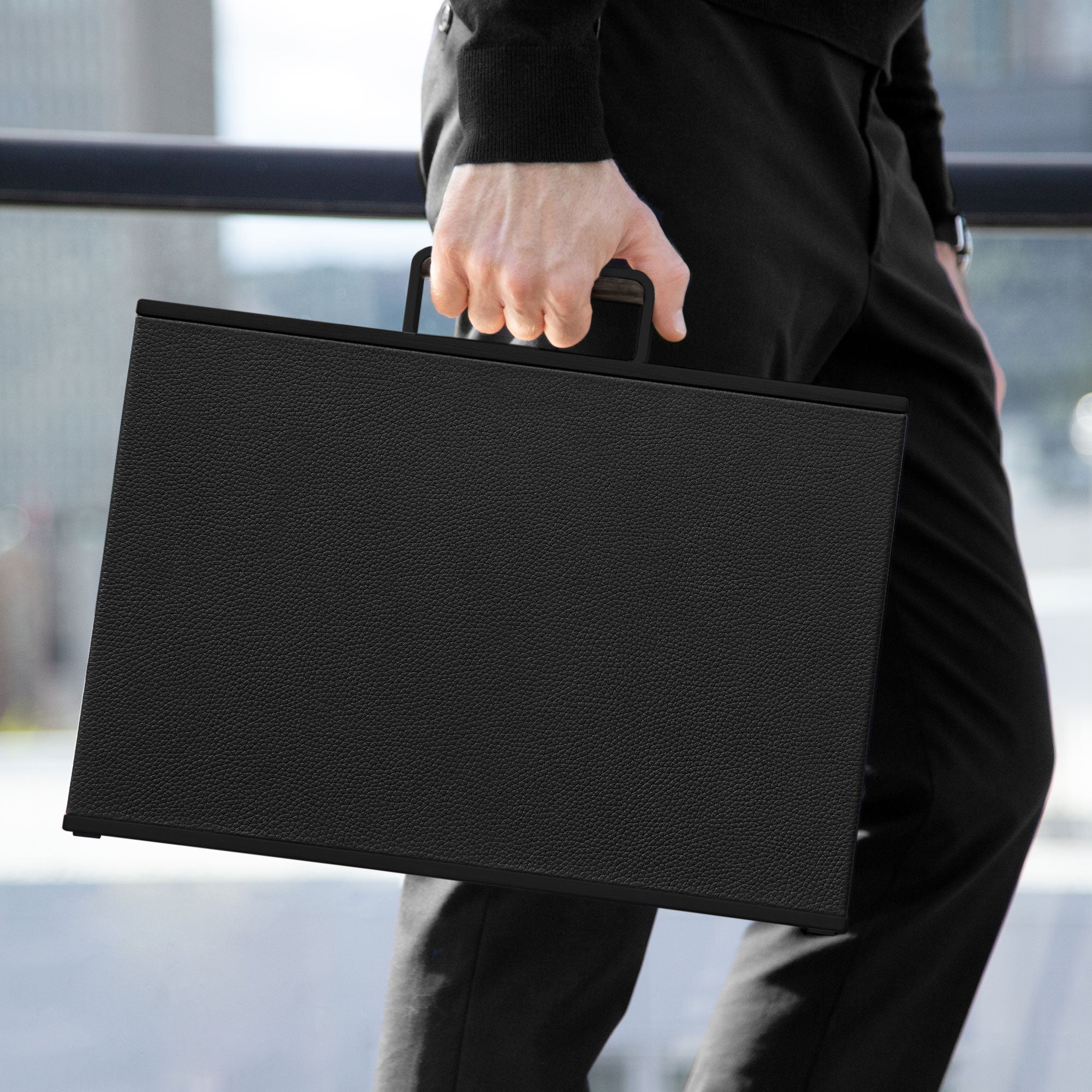 Man holding all black Mackenzie 10 Watch briefcase made by hand from young bull leather, aluminum carbon fibre and Alcantara interior
