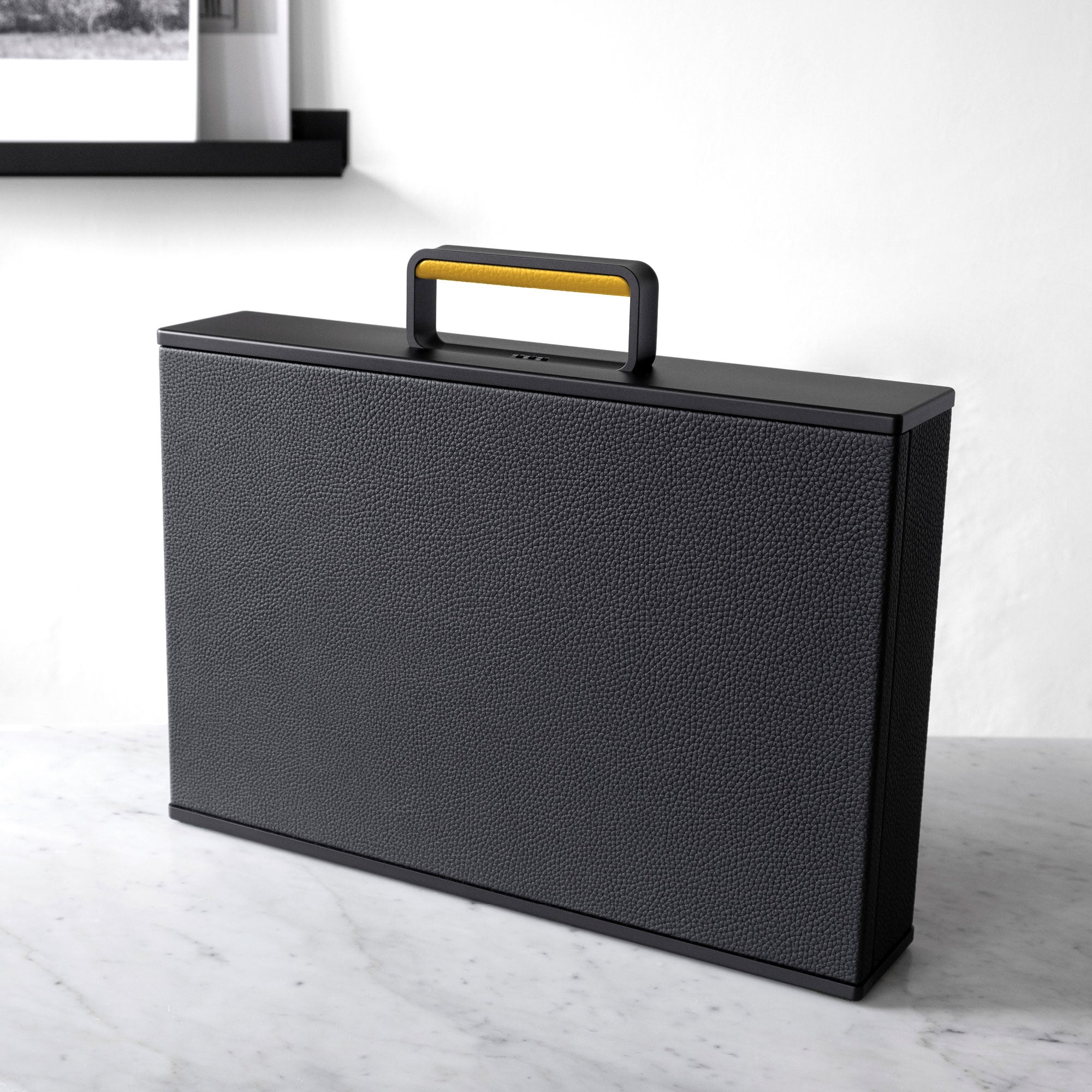 Lifestyle photo showing the vibrant sunflower leather handle detail and black leather of this boldly minimalist briefcase