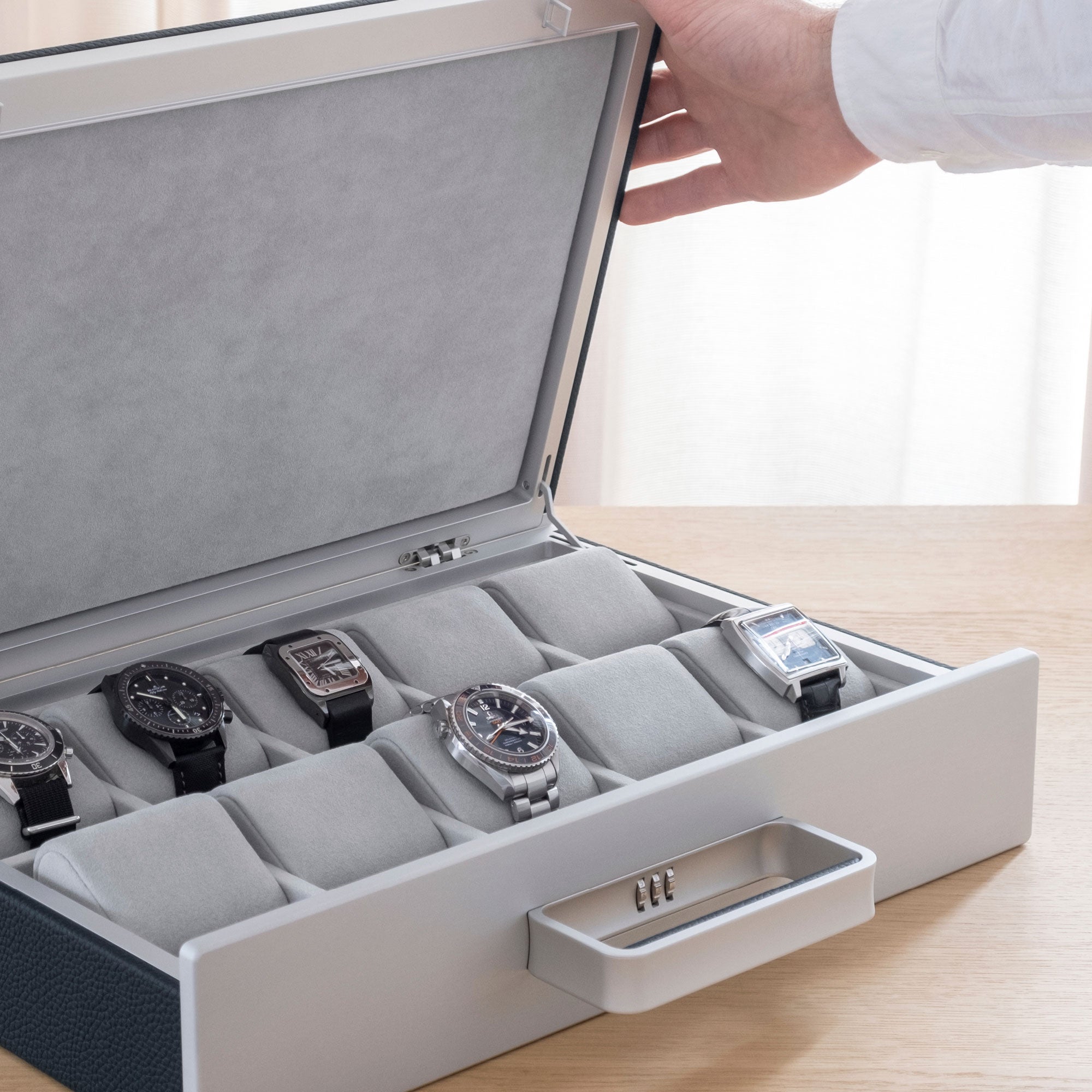 Lifestyle photo of man opening the Mackenzie 10 watch briefcase in marine leather and fog grey interior displaying his watch collection of men's luxury watches