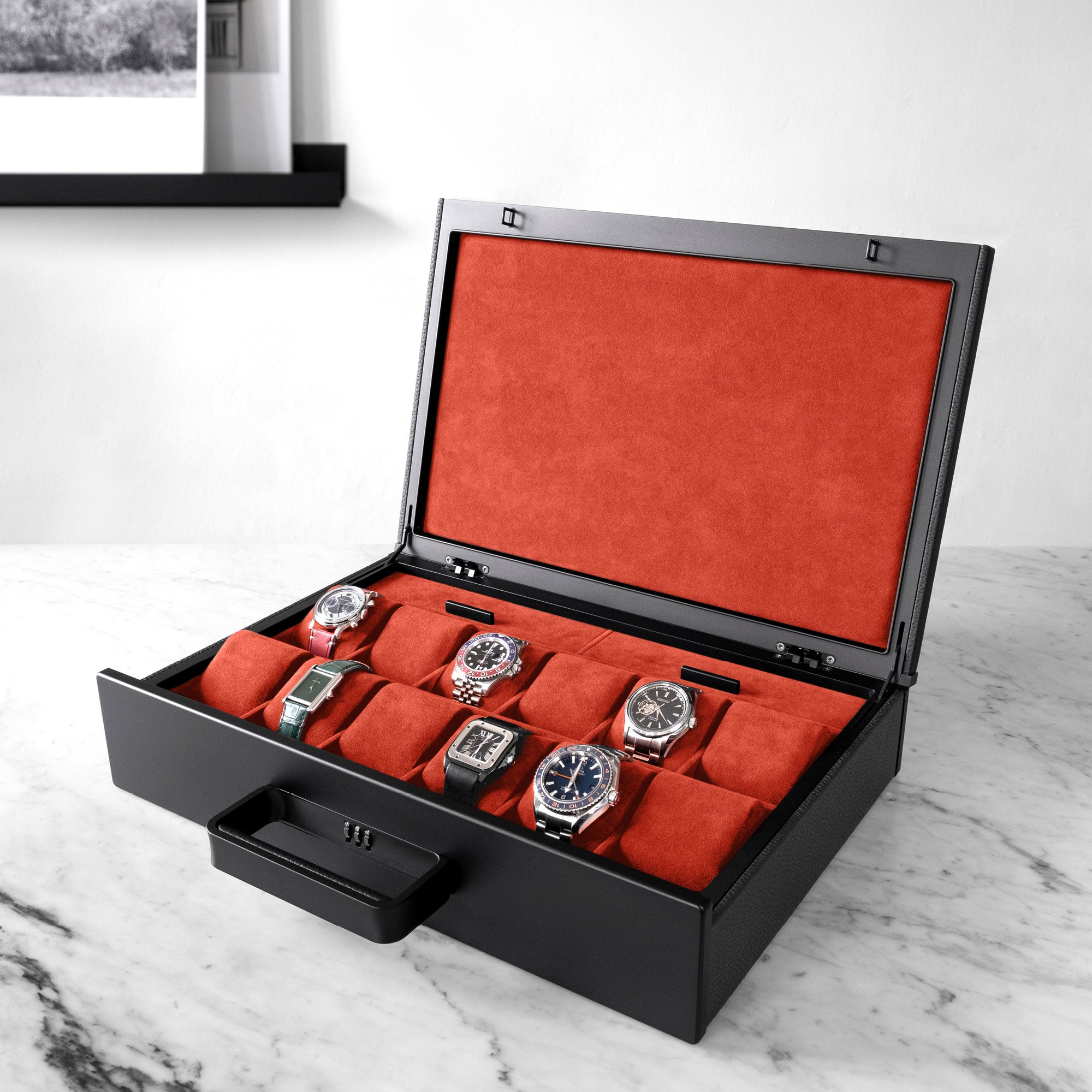 Lifestyle shot of open Mackenzie 12 Watch briefcase in carbon fiber and black aluminum casing, black leather and soft vermilion Alcantara made by hand filled with luxury watches including Rolex, Cartier and Omega