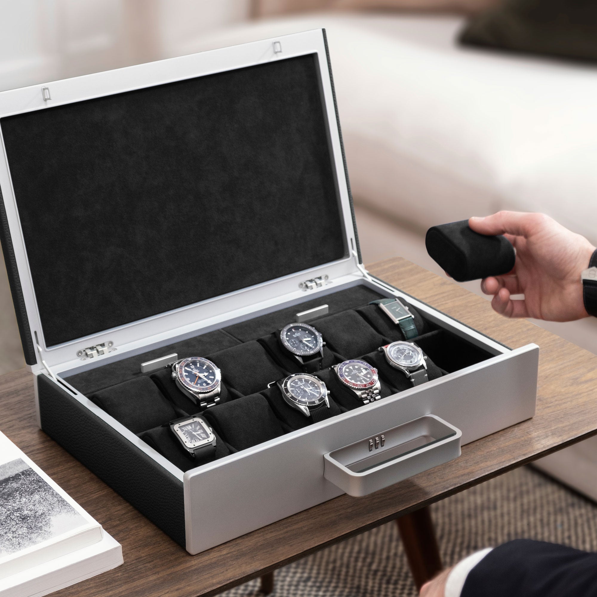 Lifestyle shot of open Mackenzie 12 Watch briefcase in carbon fiber and grey anodized aluminum casing, black leather and soft notte Alcantara made by hand filled with luxury watches including Rolex, Jaeger-LeCoultre, Blancpain and Omega