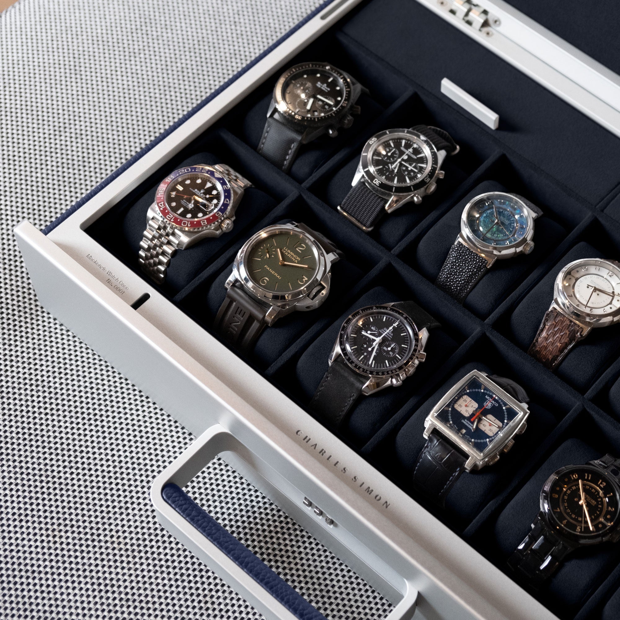 Lifestyle shot of sapphire Mackenzie watch briefcase filled with luxury watches including Rolex, Panerai and Omega