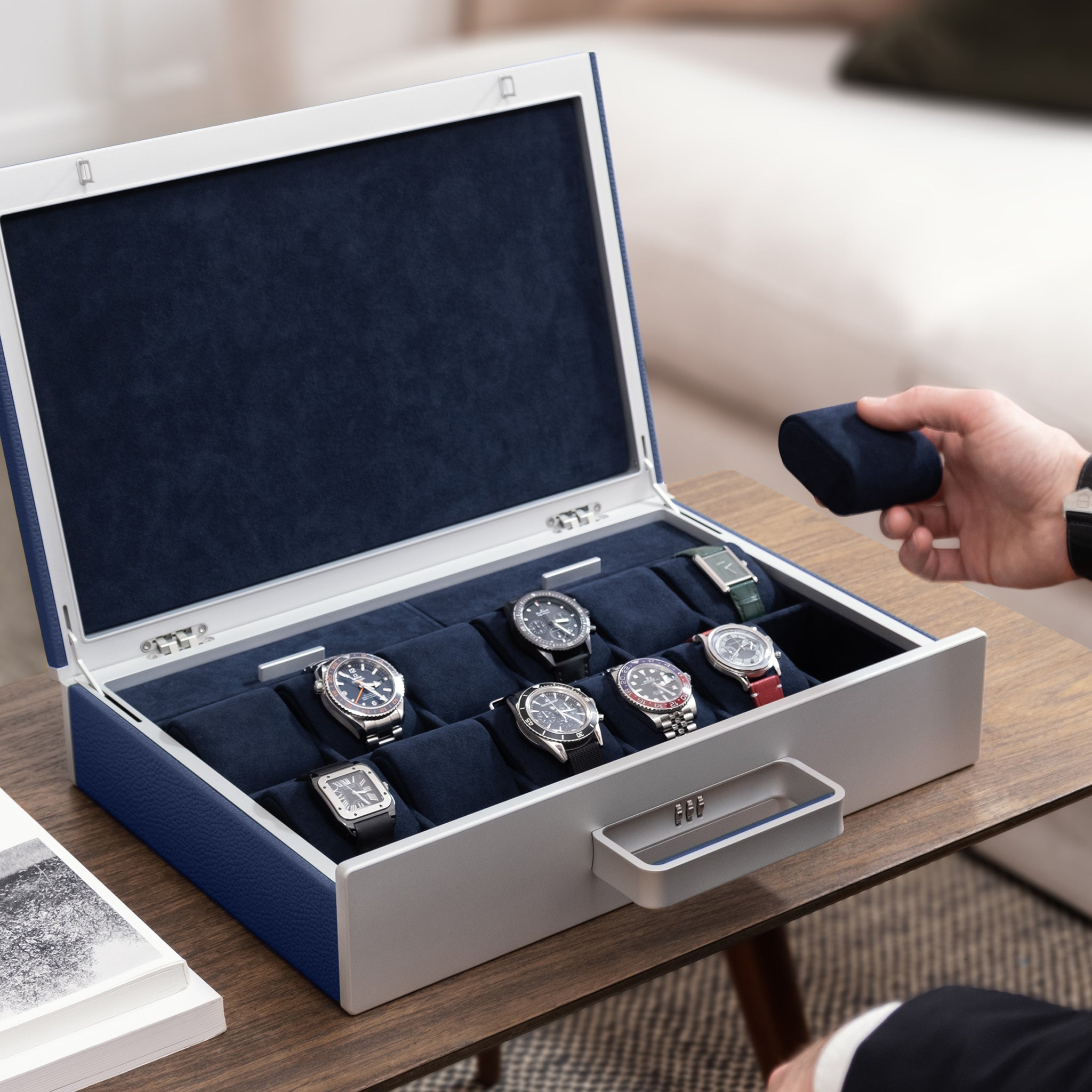 Lifestyle picture of man taking deep blue removable Alcantara cushion from sapphire Mackenzie watch briefcase holding 7 luxury watches including Rolex, Omega and Cartier