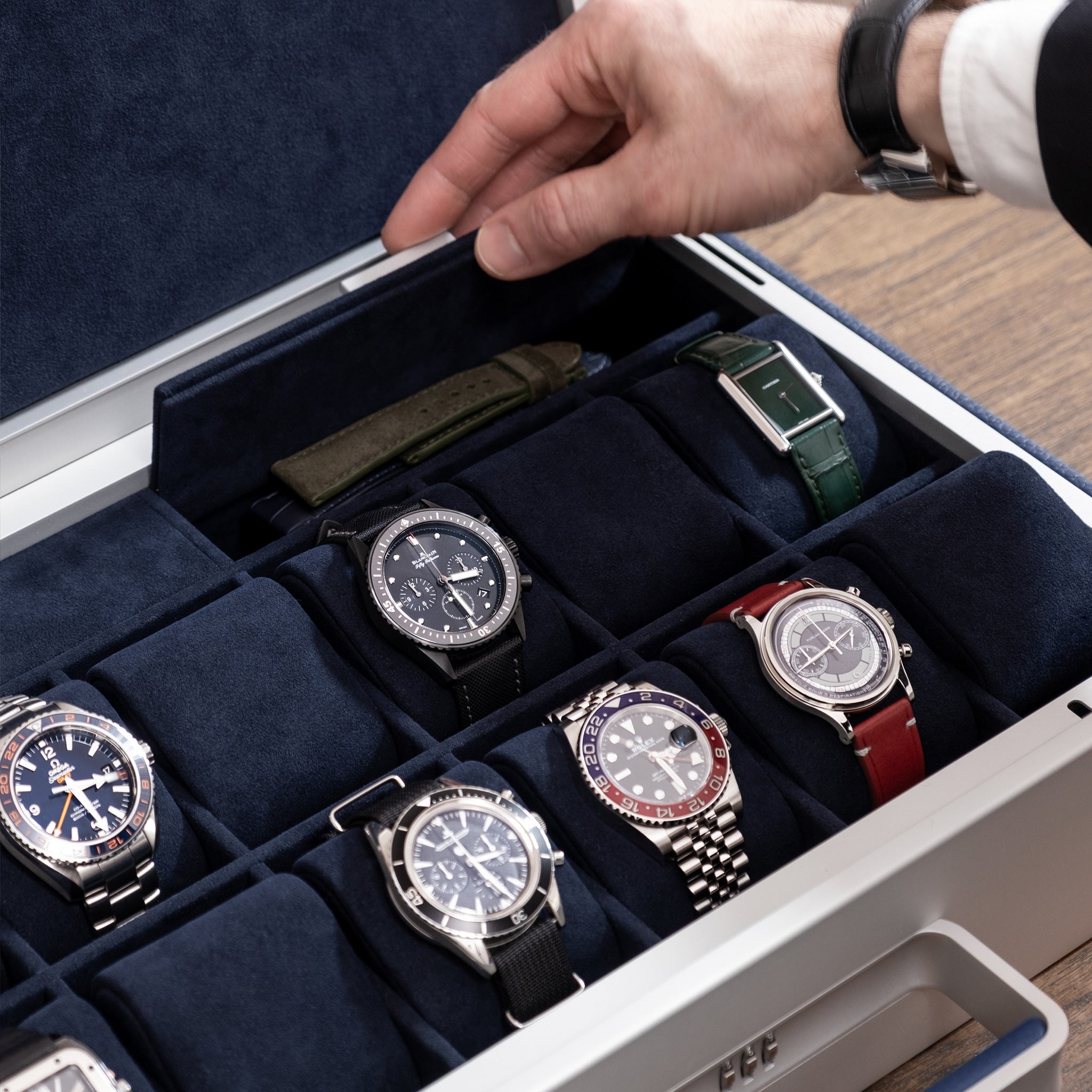 Lifestyle photo of man opening storage compartment of the Mackenzie 12 luxury watch briefcase in sapphire leather and deep blue Alcantara containing watch straps and other watch accessories 