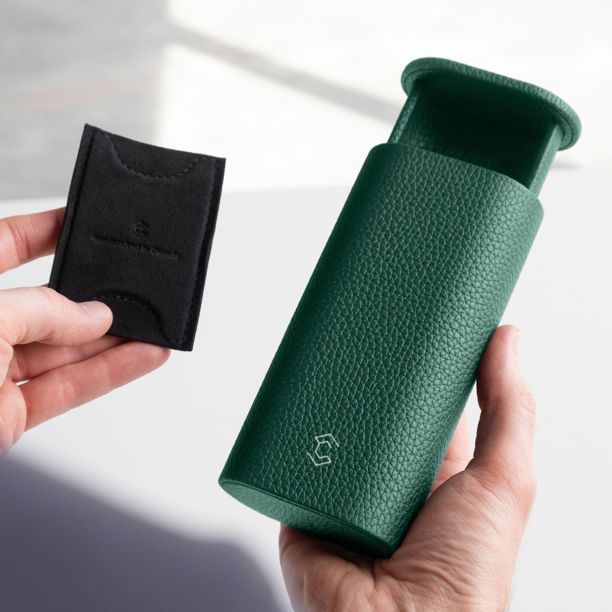 Man holding emerald green Oscar 1 Tall Leather Watch roll in his right hand and the card insert that holds the watch in place within the watch roll in the left hand.