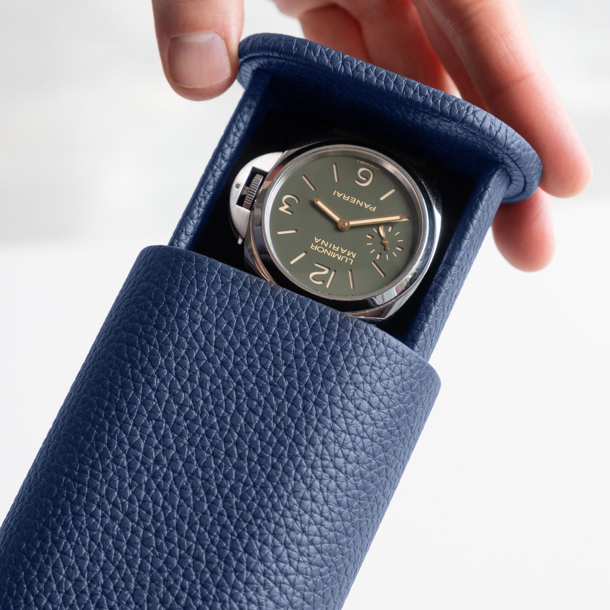 Detail photo of man sliding open sapphire leather Oscar Tall Travel Watch roll with a luxury men's watch inside