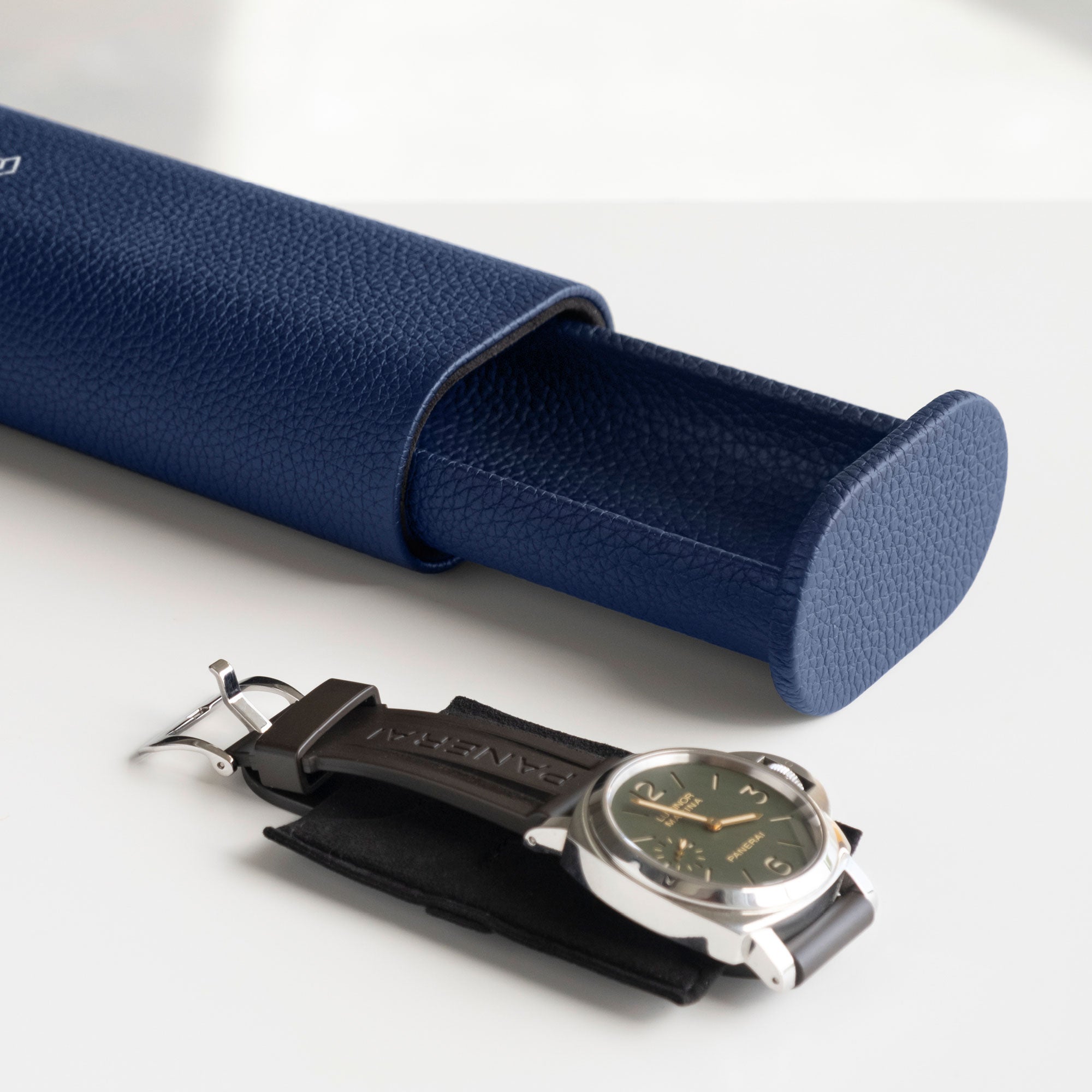 Open Oscar Tall Travel Watch roll in sapphire leather with Panerai watch with a rubber strap placed on the Alcantara card insert in the foreground to keep the watch in place 