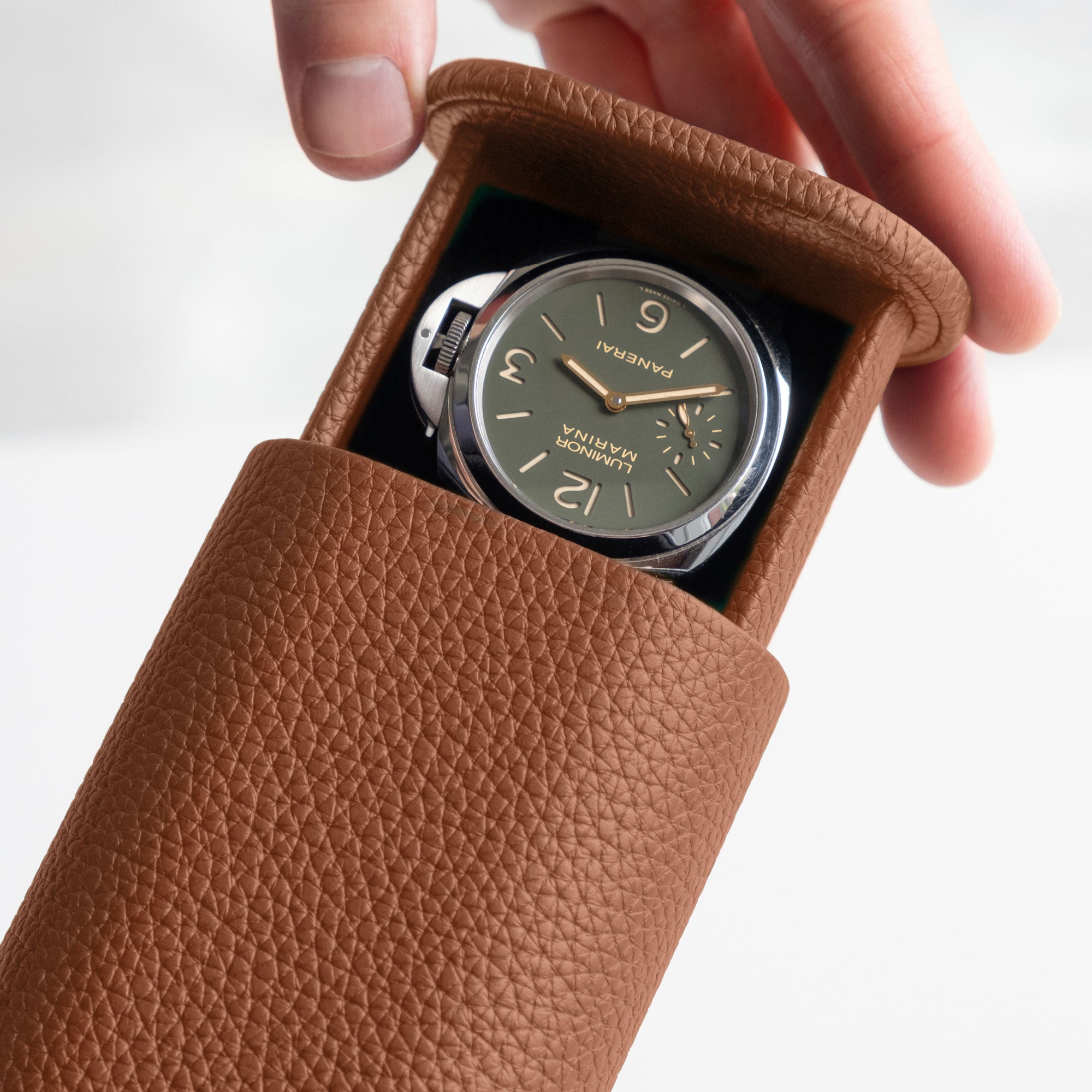Detail photo of man opening the Oscar Tall Travel Watch roll in tan leather to reveal a Panerai watch held inside.