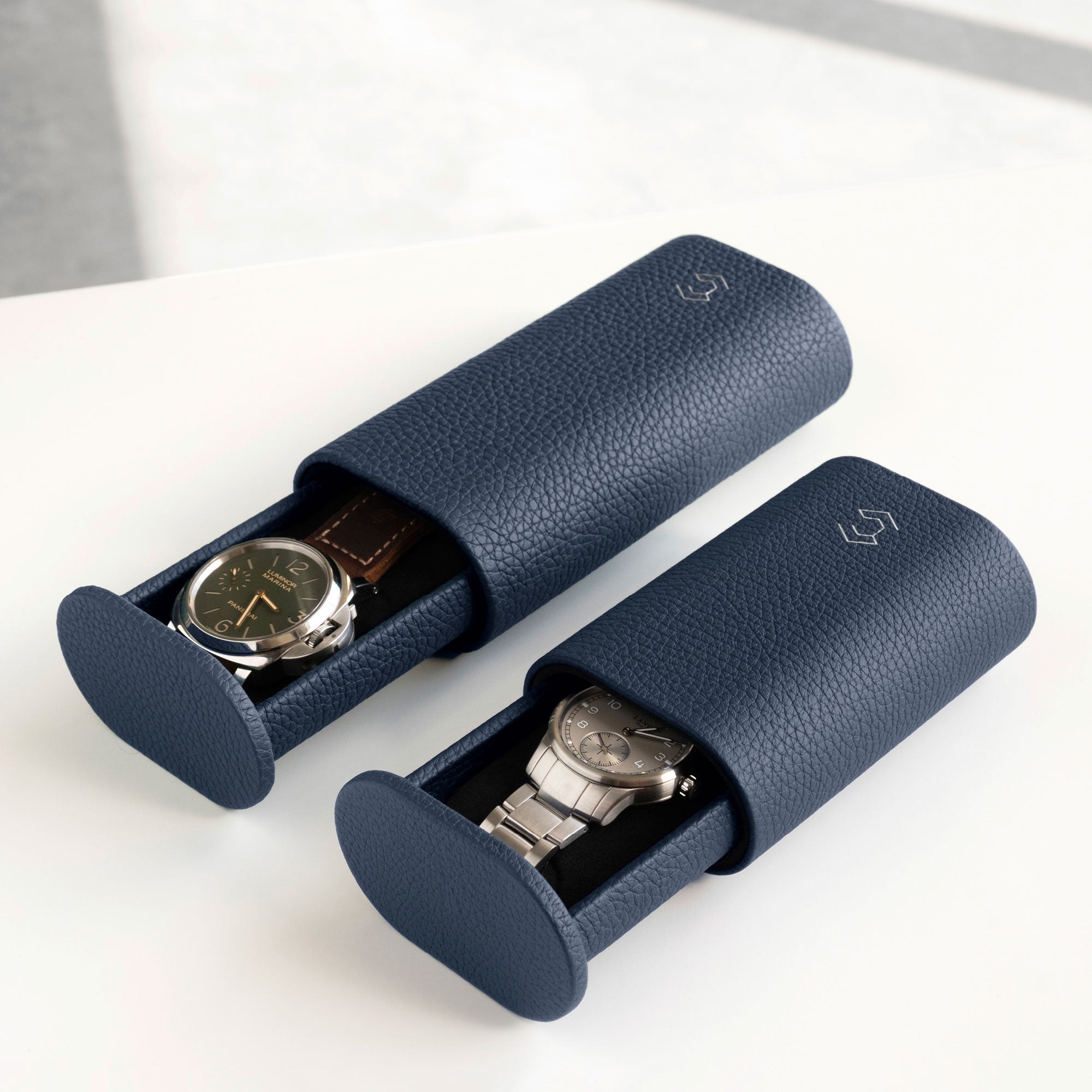 Lifestyle photo of two Oscar watch rolls in marine leather side by side. The Oscar 1 Tall for watches with a watch strap on the left and the Oscar 1 for watches with a metal bracelet on the right