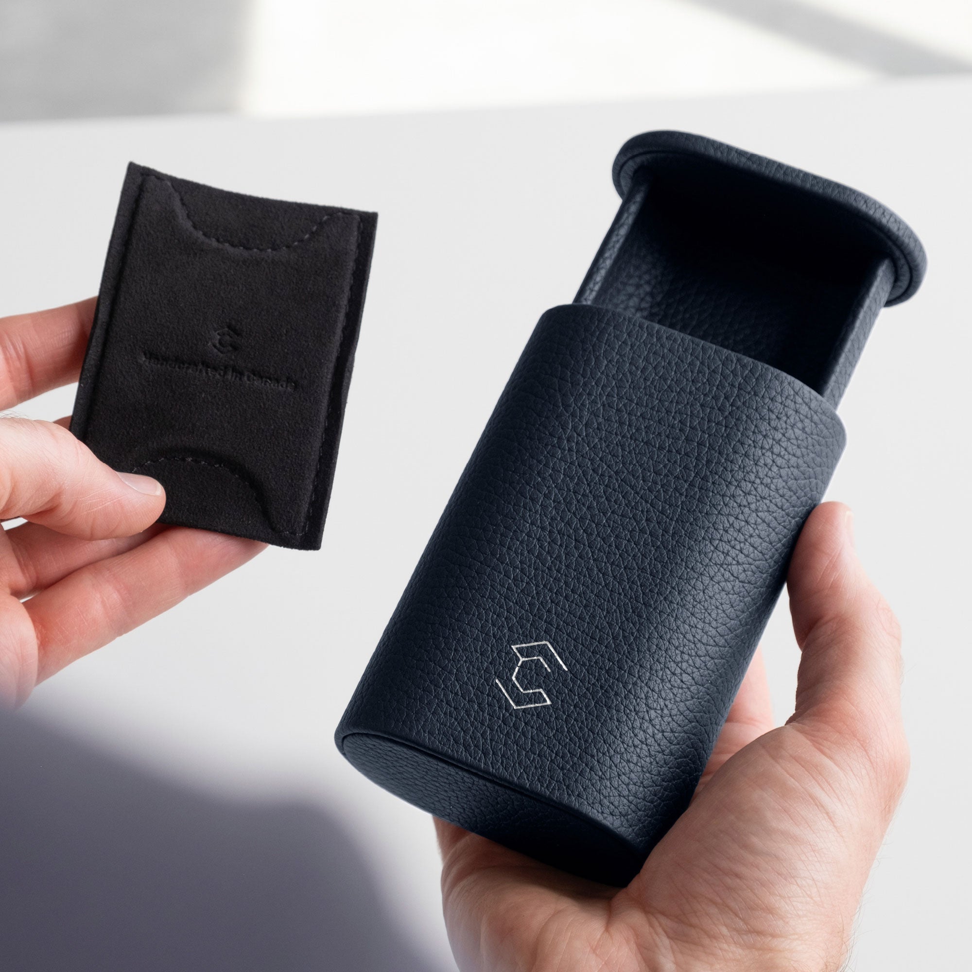 Man holding marine leather Oscar Travel Watch roll in one hand and the card insert to hold the watch in place in the left hand.