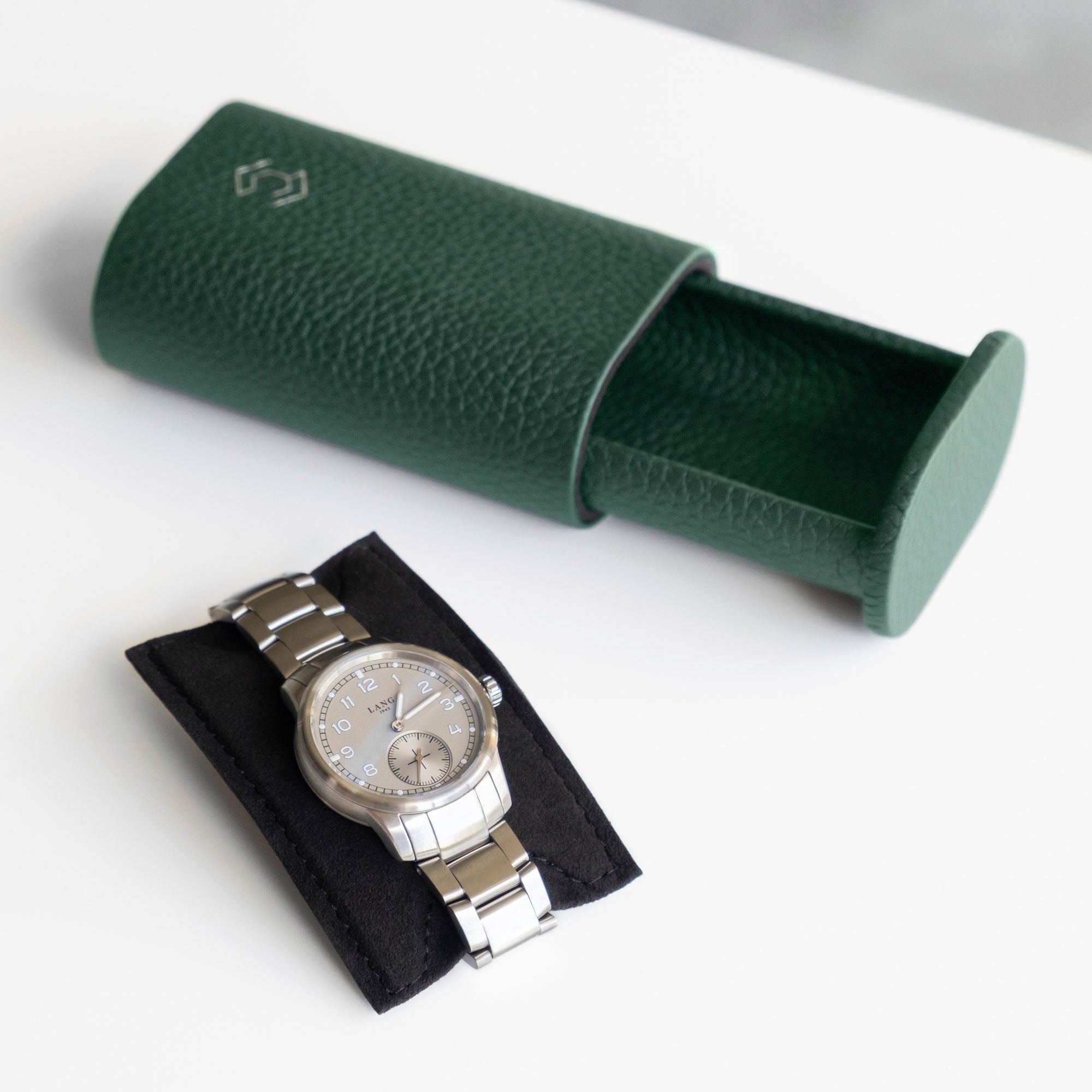 Open emerald leather watch roll by Charles Simon with mens watch placed on removable card insert in the foreground.