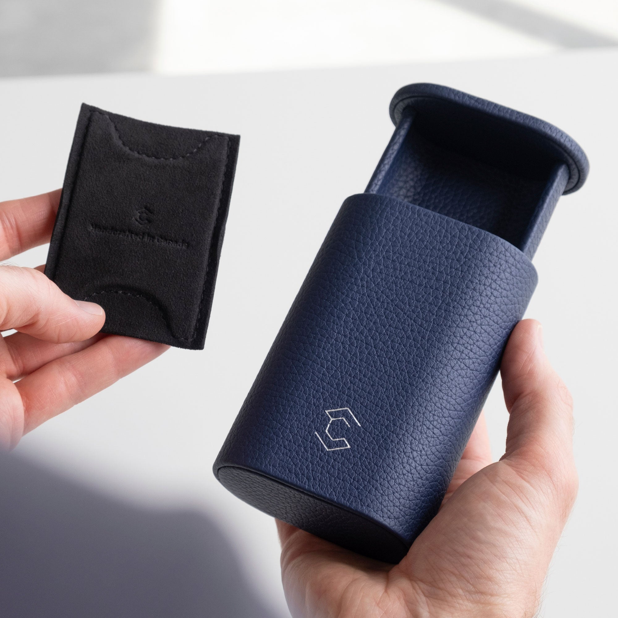 Man holding open sapphire leather Oscar watch roll in one hand and the removable card insert that keeps the timepiece in place in the other hand.