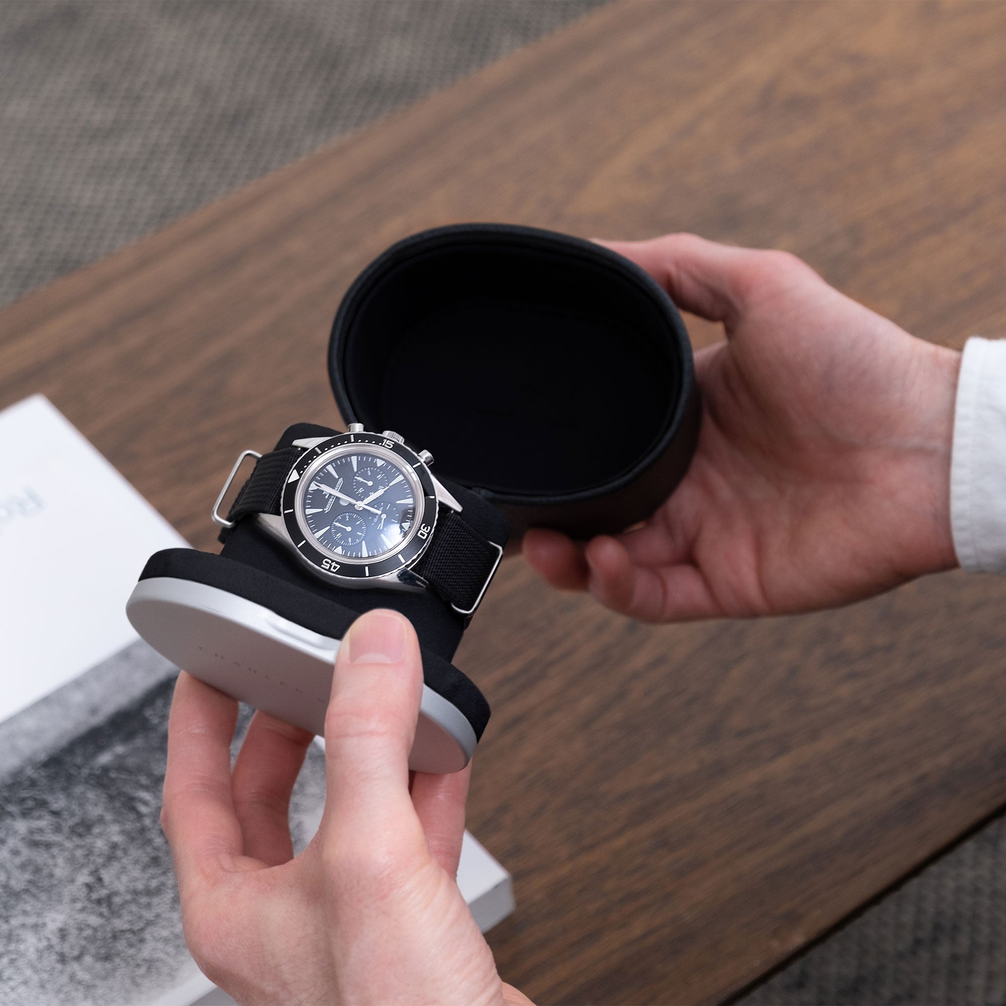 Lifestyle photo of business man opening luxury Theo leather watch roll in Notte Alcantara and black Taurillon leather holding one designer watch
