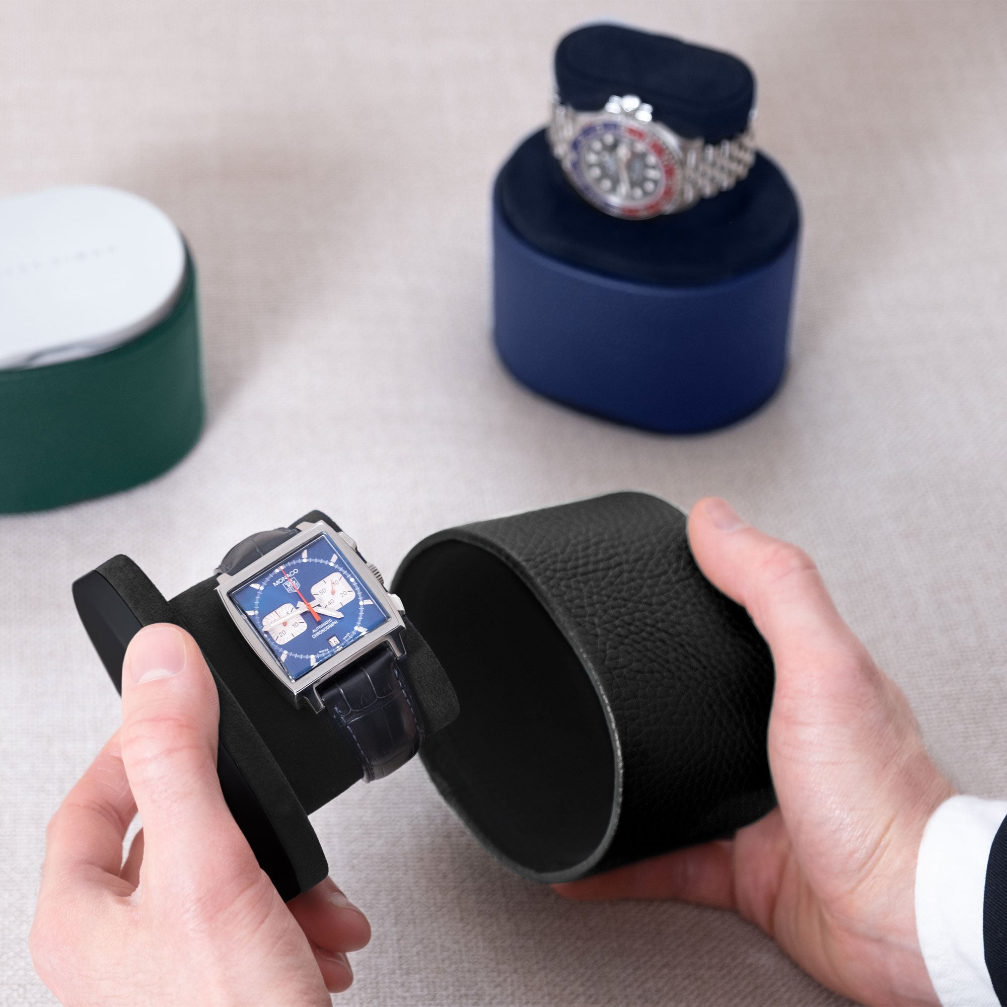 Lifestyle photo of open Theo handmade travel watch roll in black leather and notte interior holding Tag Heuer Monaco luxury watch