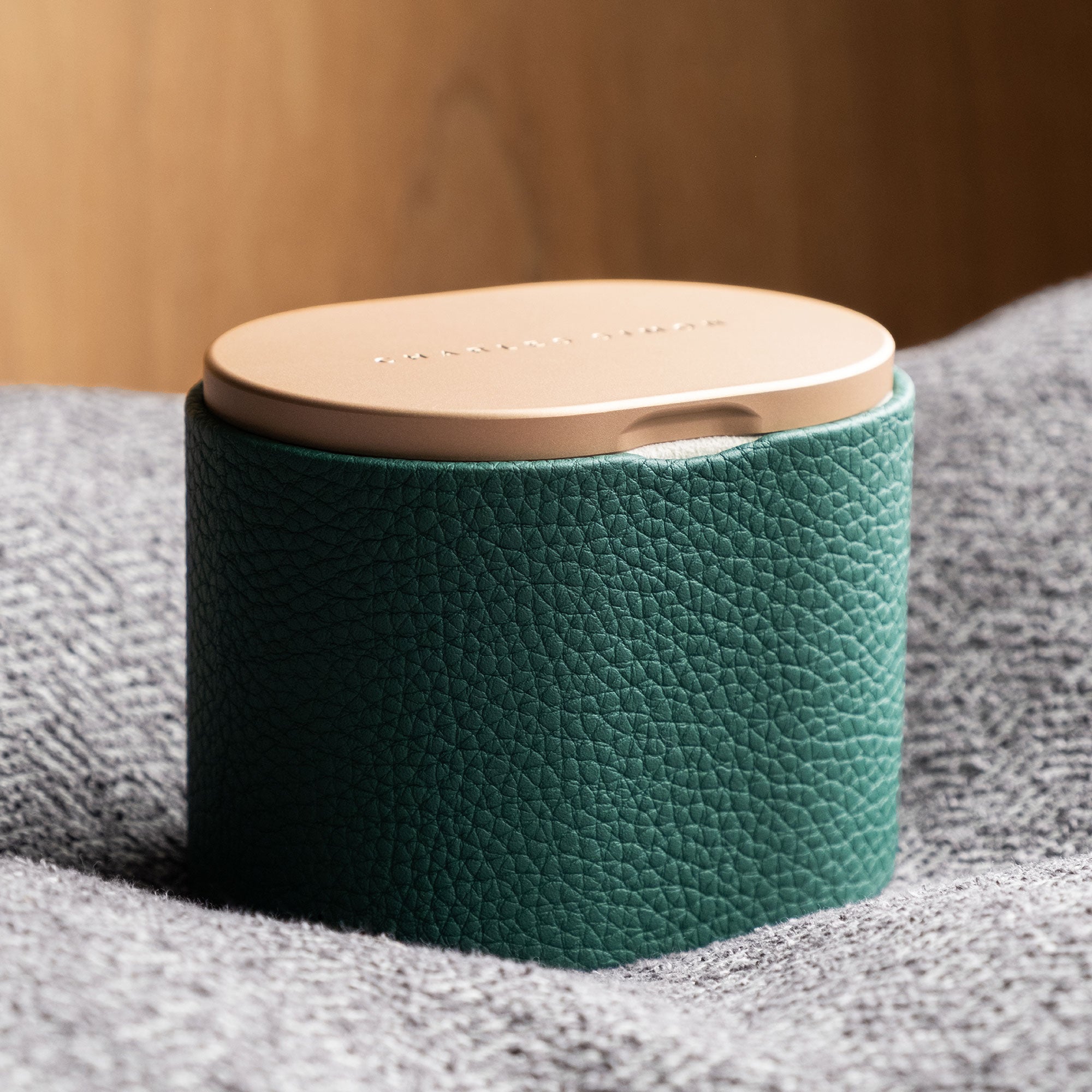 Lifestyle photo of closed golden luxury Leather watch roll by Charles Simon. Handcrafted from emerald Taurillon leather to hold 1 timepiece while traveling.