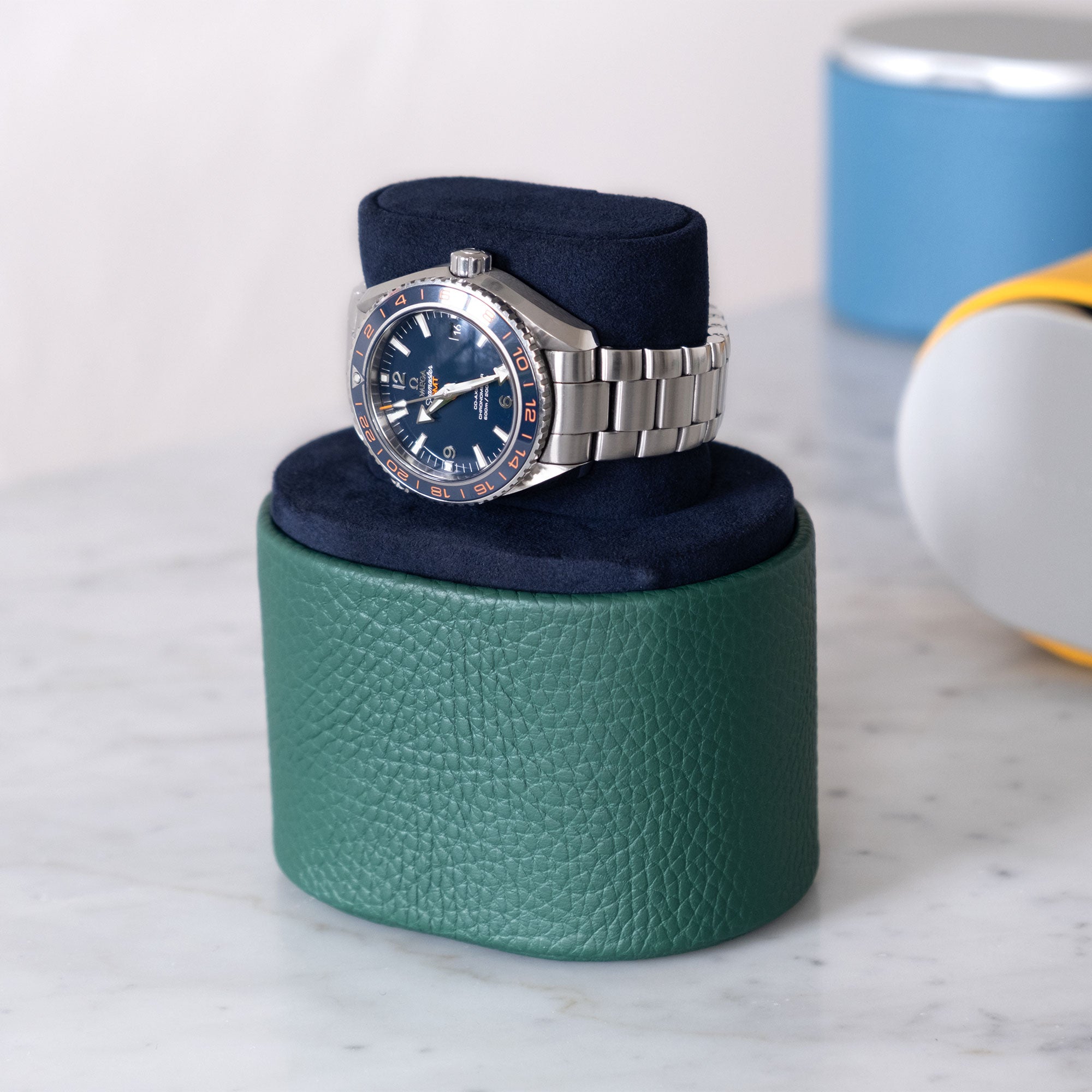 Lifestyle shot of handmade Theo watch roll in emerald leather and deep blue interior holding Tag Heuer Monaco luxury watch