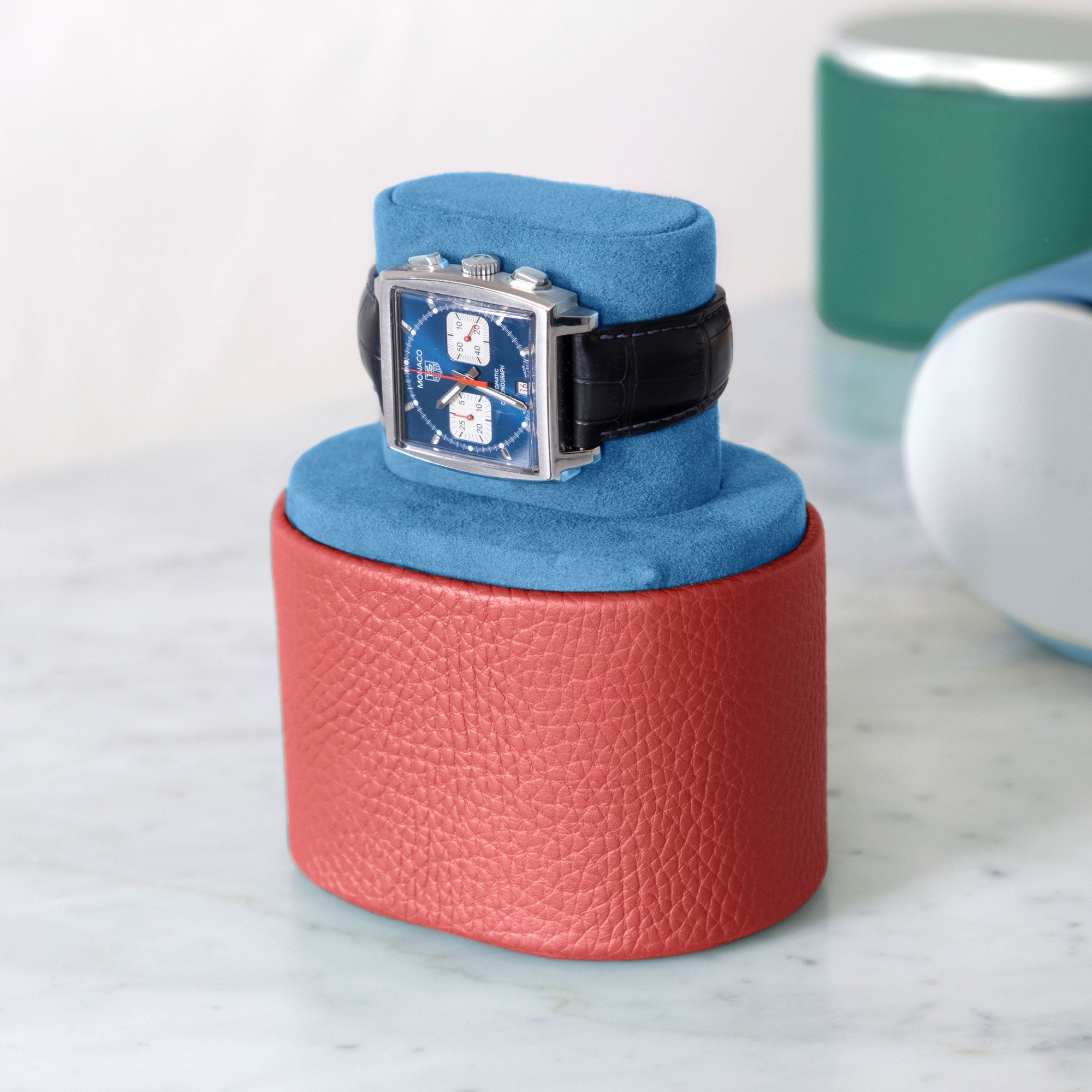 Lifestyle photo of Tagheuer Monaco luxury watch placed on Theo watch roll in hibiscus leather and Cyan blue Alcantara in watch stand position