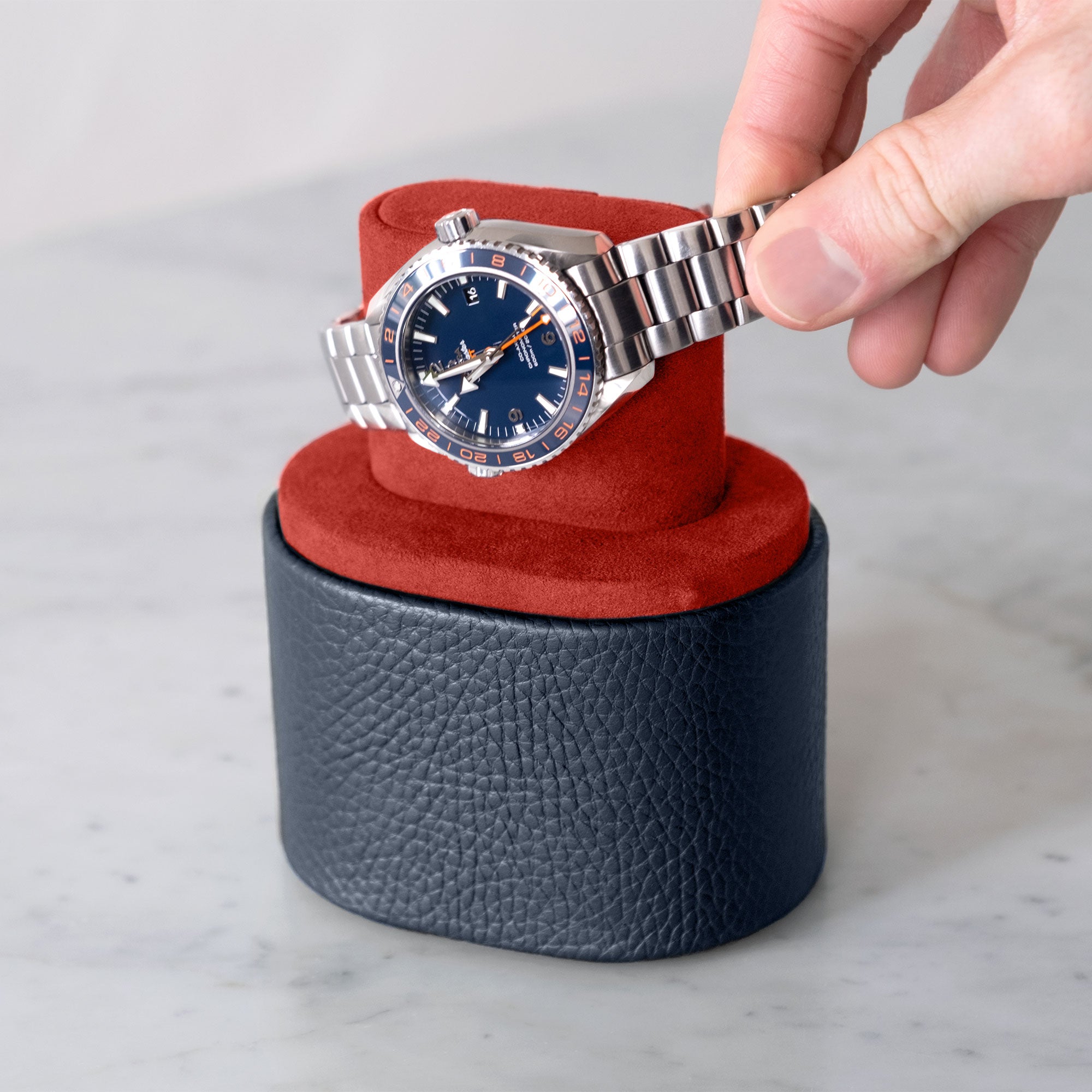 Man taking luxury watch from marine leather and vermilion Theo watch roll