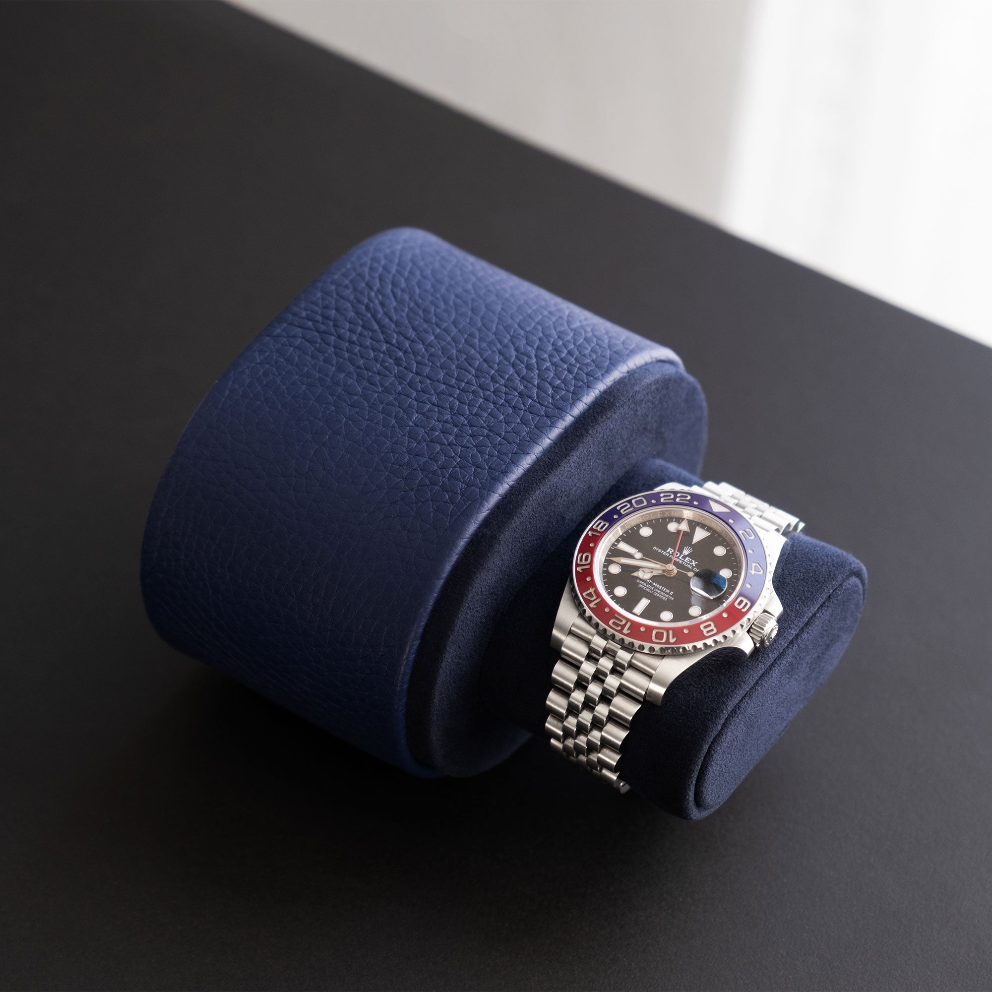 Lifestyle photo of open sapphire leather Theo watch roll for one watch displaying a Rolex Pepsi watch. 