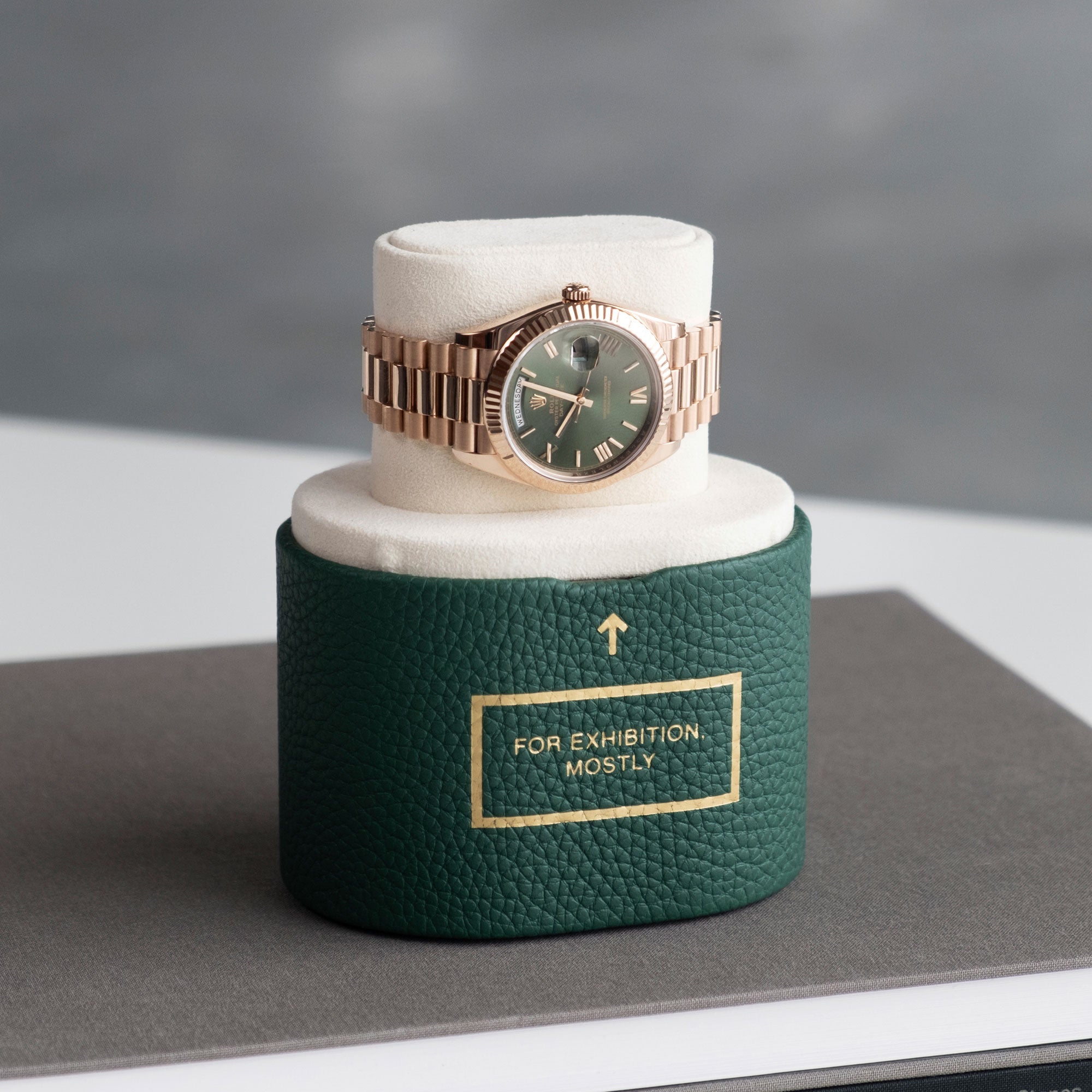 Lifestyle photo of Rolex Oyster Perpetual Day Date in gold bracelet with green dial displayed on Charles Simon x seconde/ seconde/ limited edition watch roll saying "For exibition only"