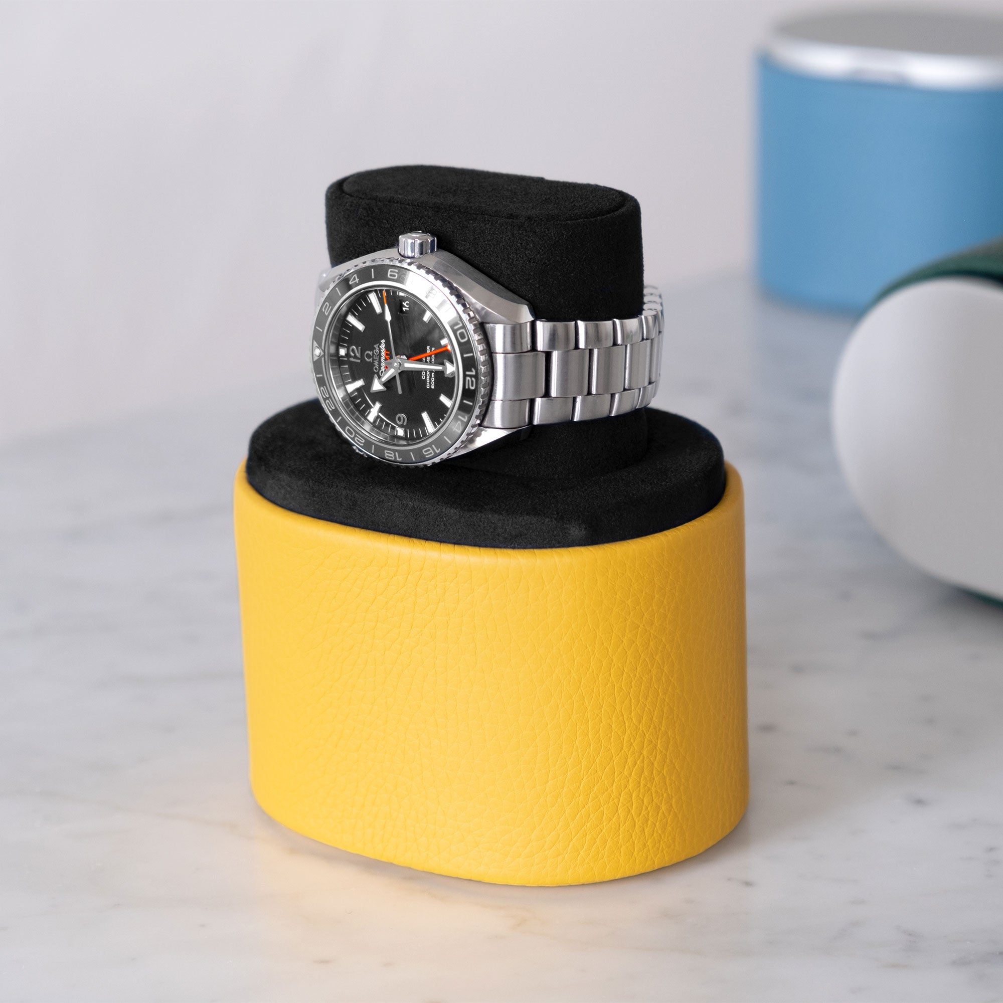 Lifestyle shot of open Theo watch roll in sunflower leather and black interior in convenient portable watch stand position holding one watch