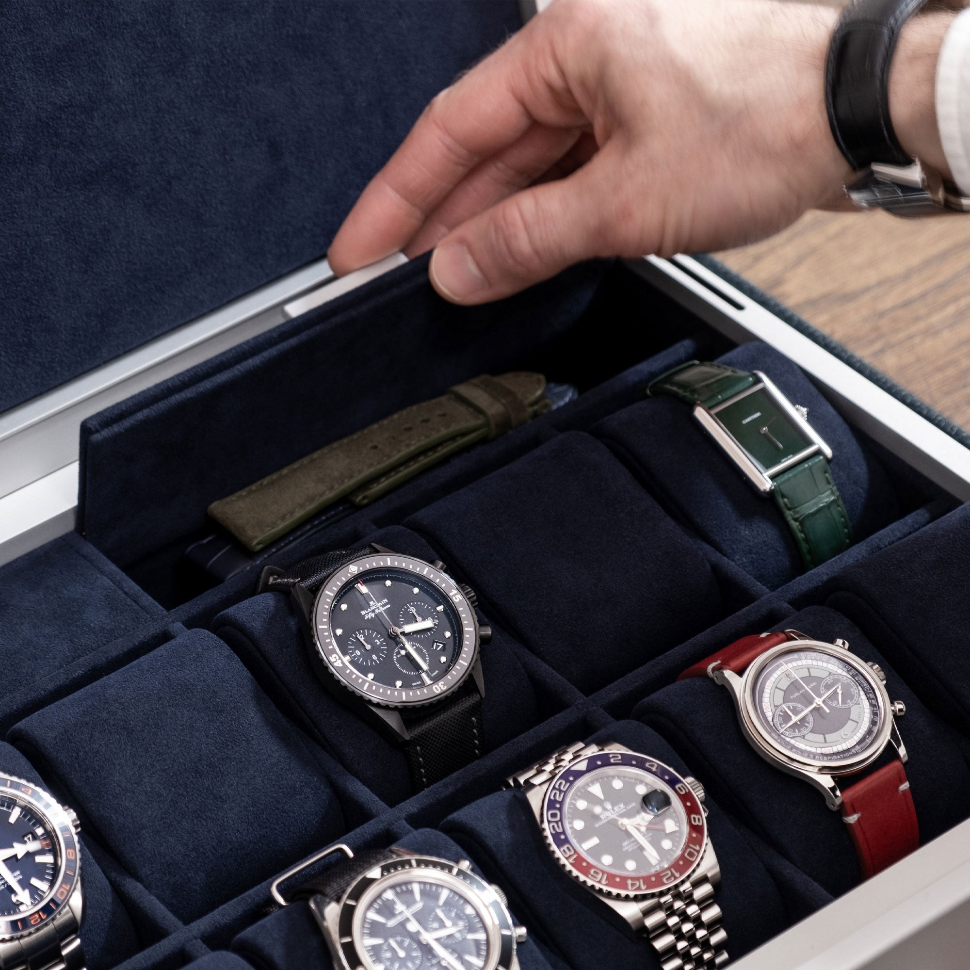 Member of the Paris Watch Club opening additional storage compartment of his grey anodized aluminum Spence 12 Watch box holding his collection of luxury watches.