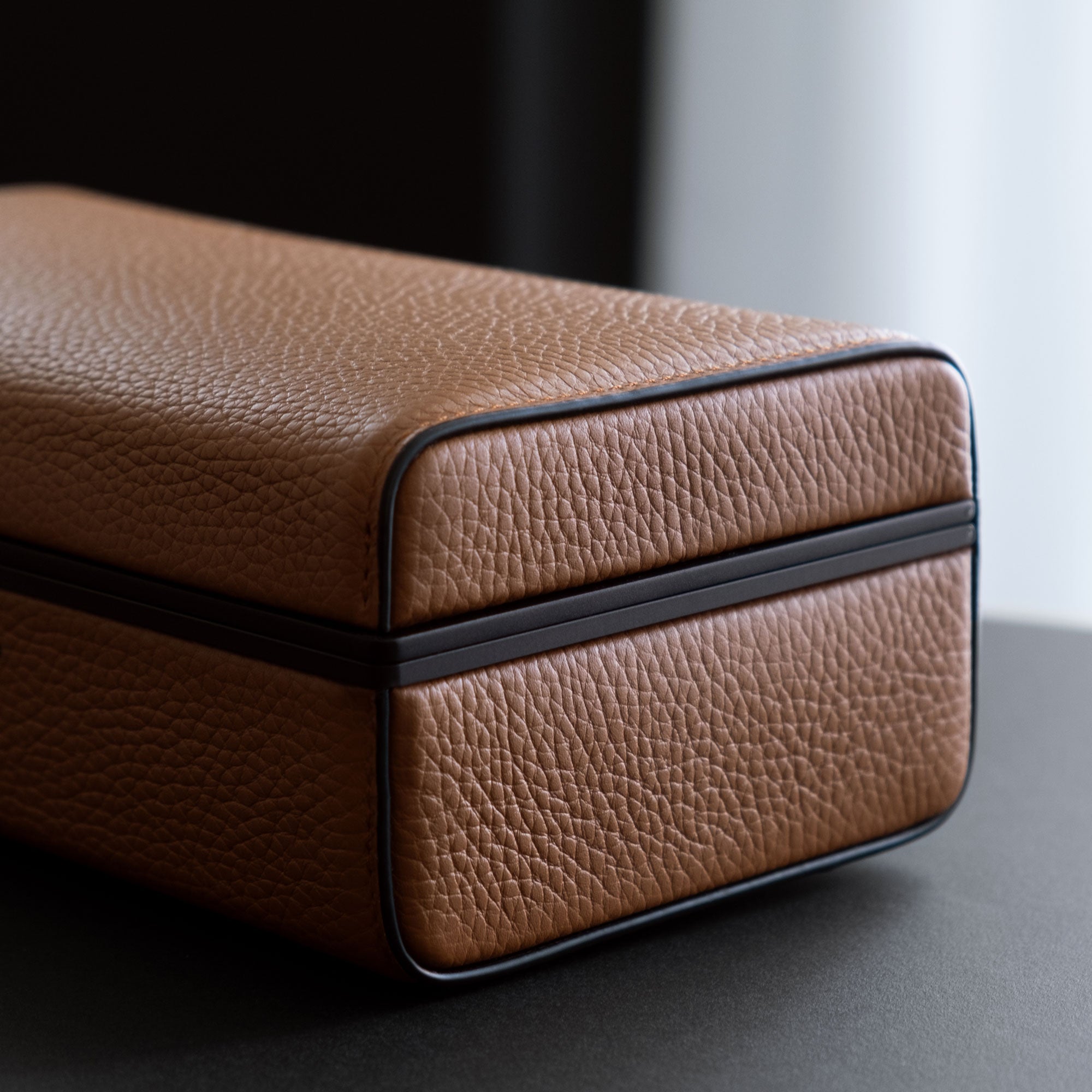 Detail shot of closed Eaton 3 watch case showing the black carbon fiber and anodized aluminum frame and tan French leather