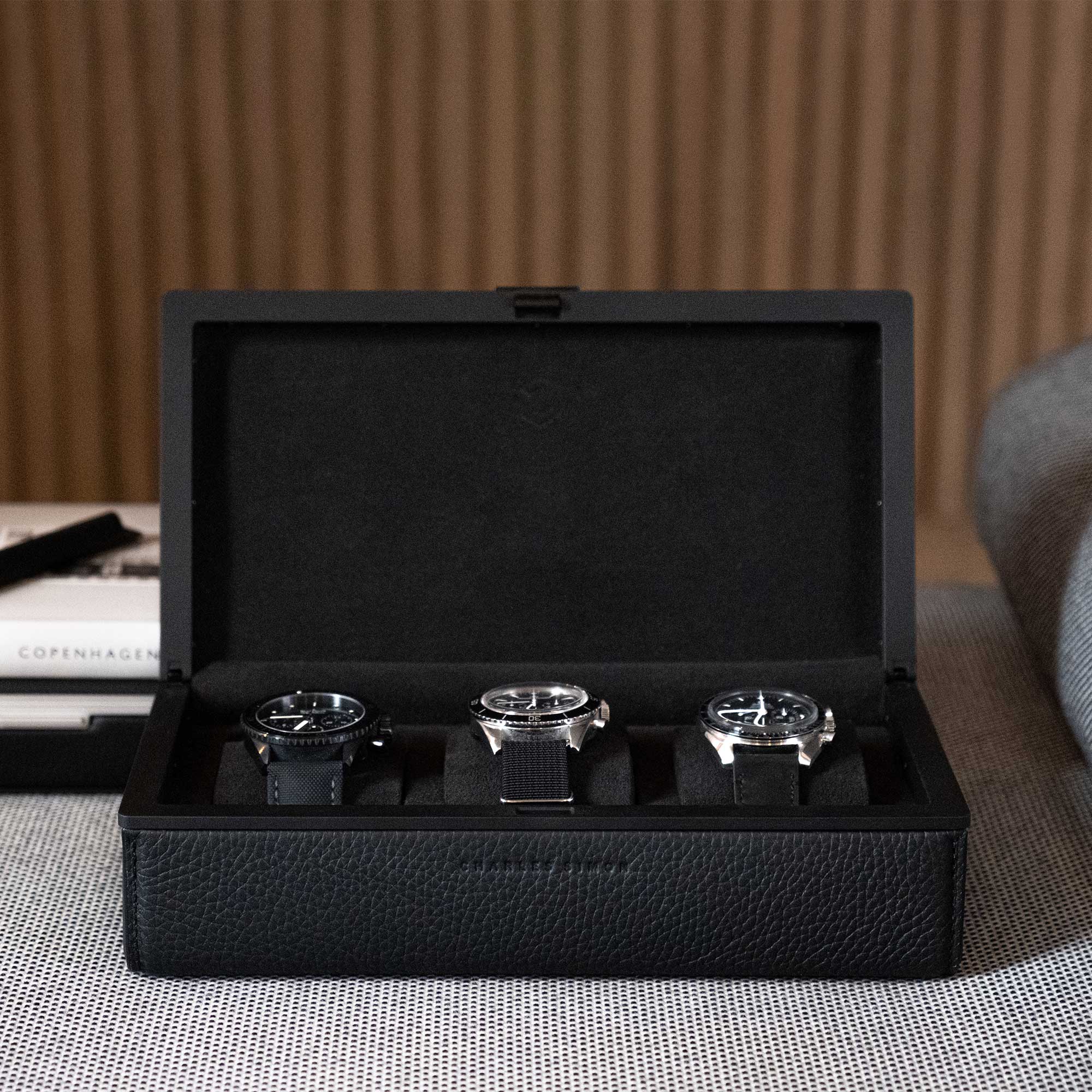 Front shot of Eaton 3 watch case in all black holding three luxury watches in modern, minimalist luxury apartment