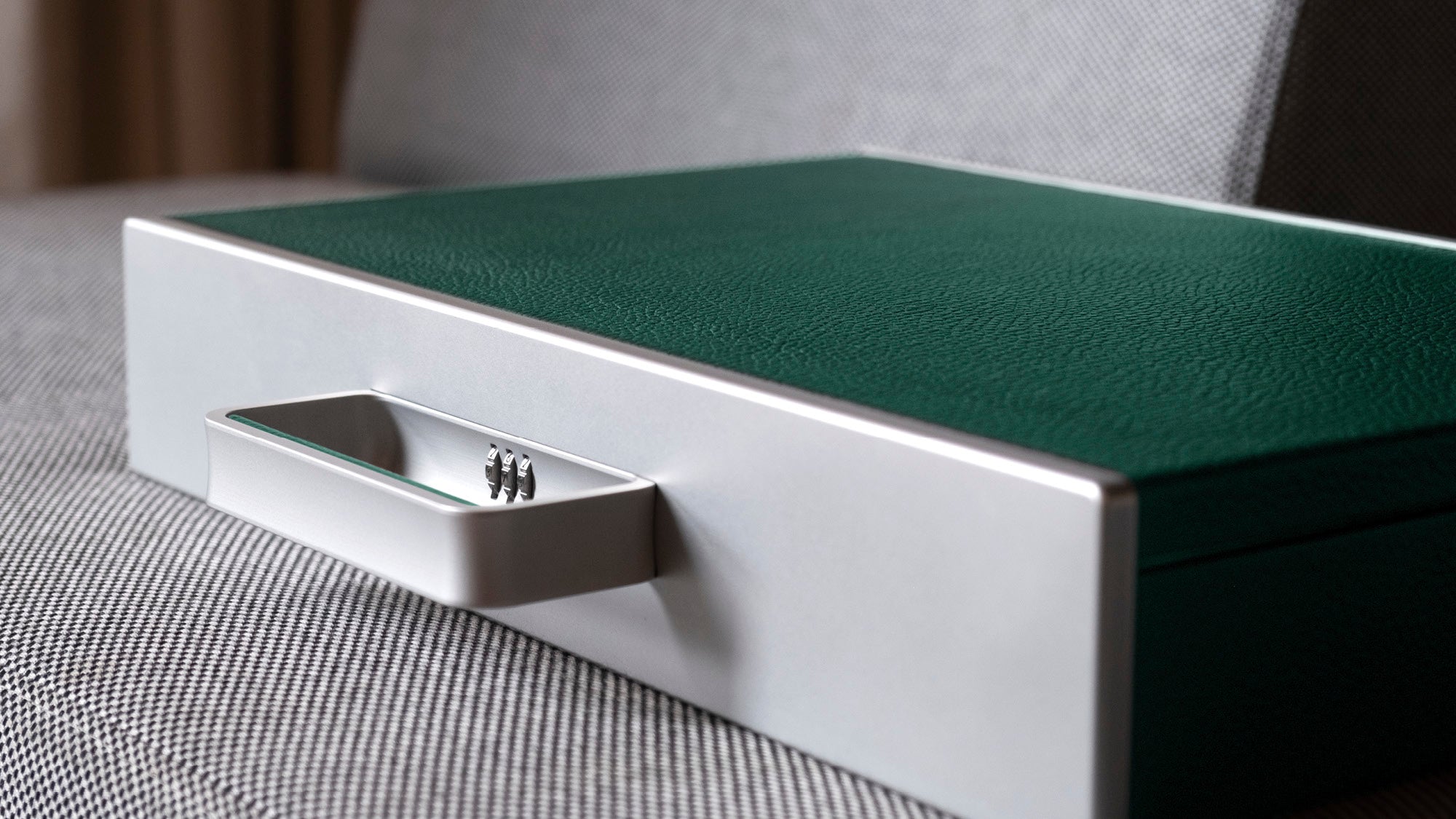 Detail photo of minimalist handle and protective lock of the emerald leather Mackenzie Briefcase