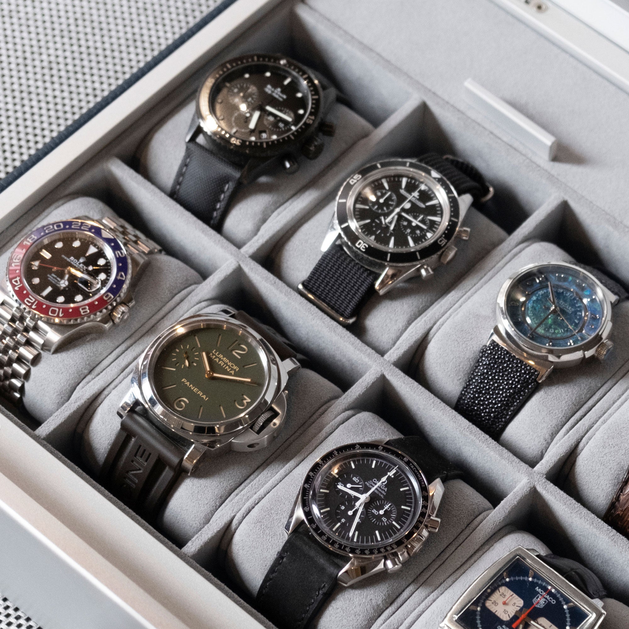 Lifestyle photo of luxury watches displayed on removable fog grey watch cushions of the Spence 12 Watch box