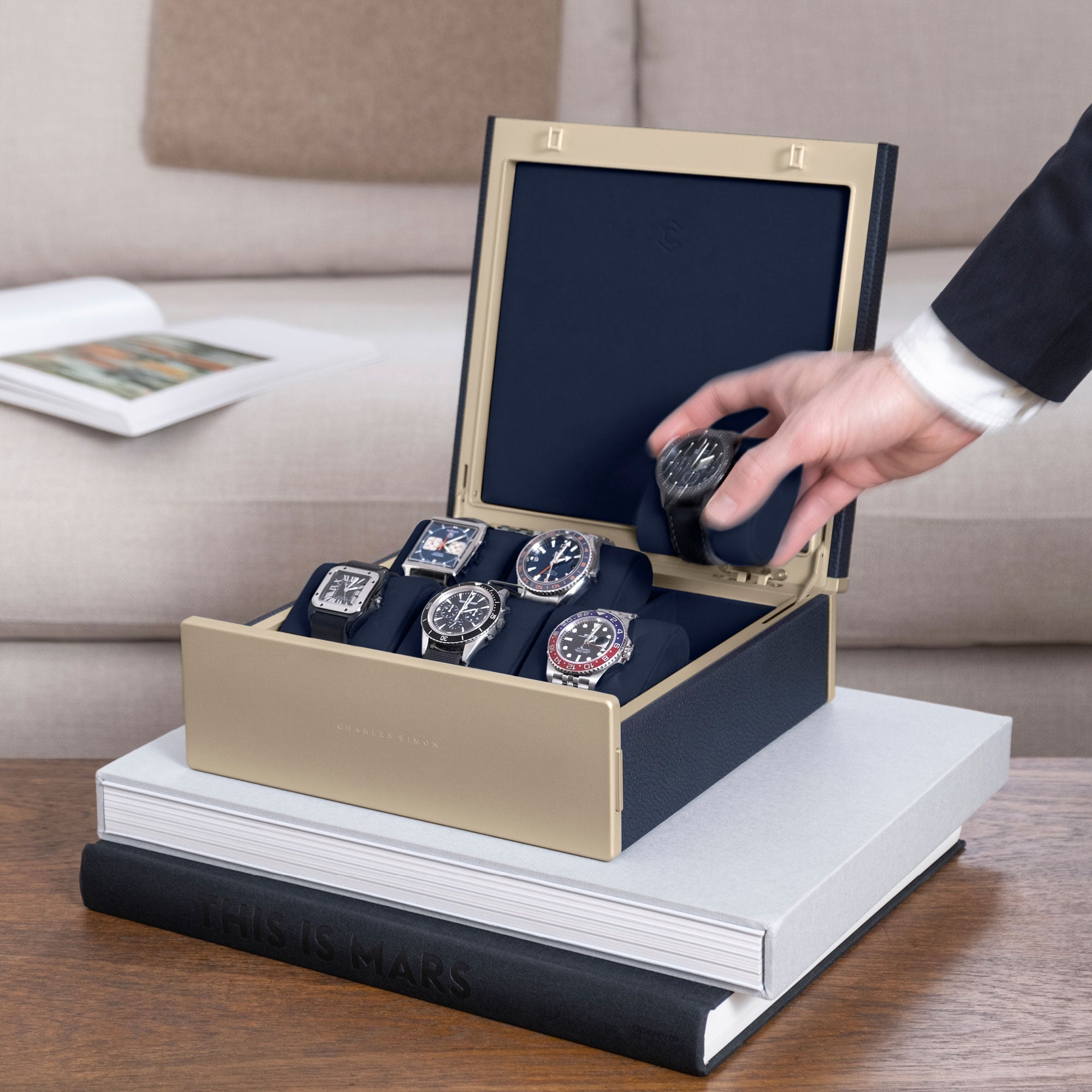 Lifestyle photo of man taking luxury watch from his gold Spence watch box in marine leather, holding his watch collection of 6 watches