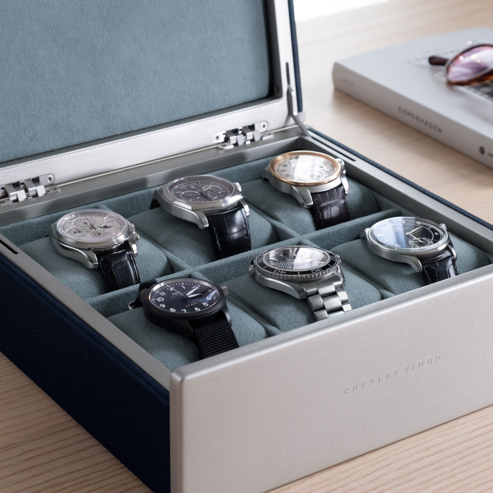 Lifestyle shot of luxury watches in Spence watch box for 6 watches. Made from smoky blue Alcantara interior and marine leather
