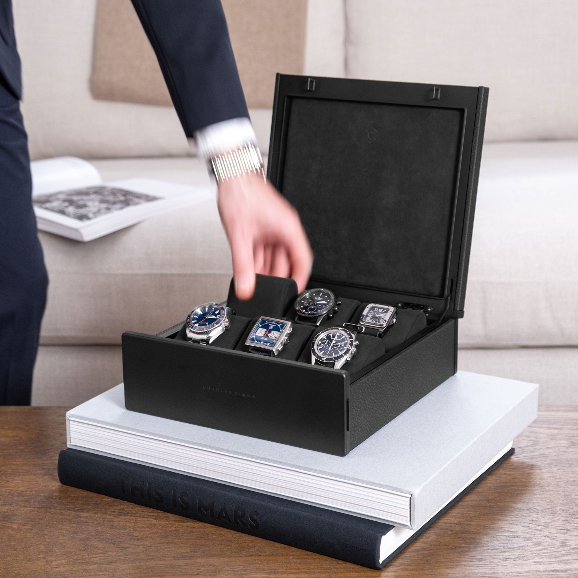 Lifestyle shot of a gentleman taking a removable Alcantara cushion from an all black Spence 6 watch box for watch collectors