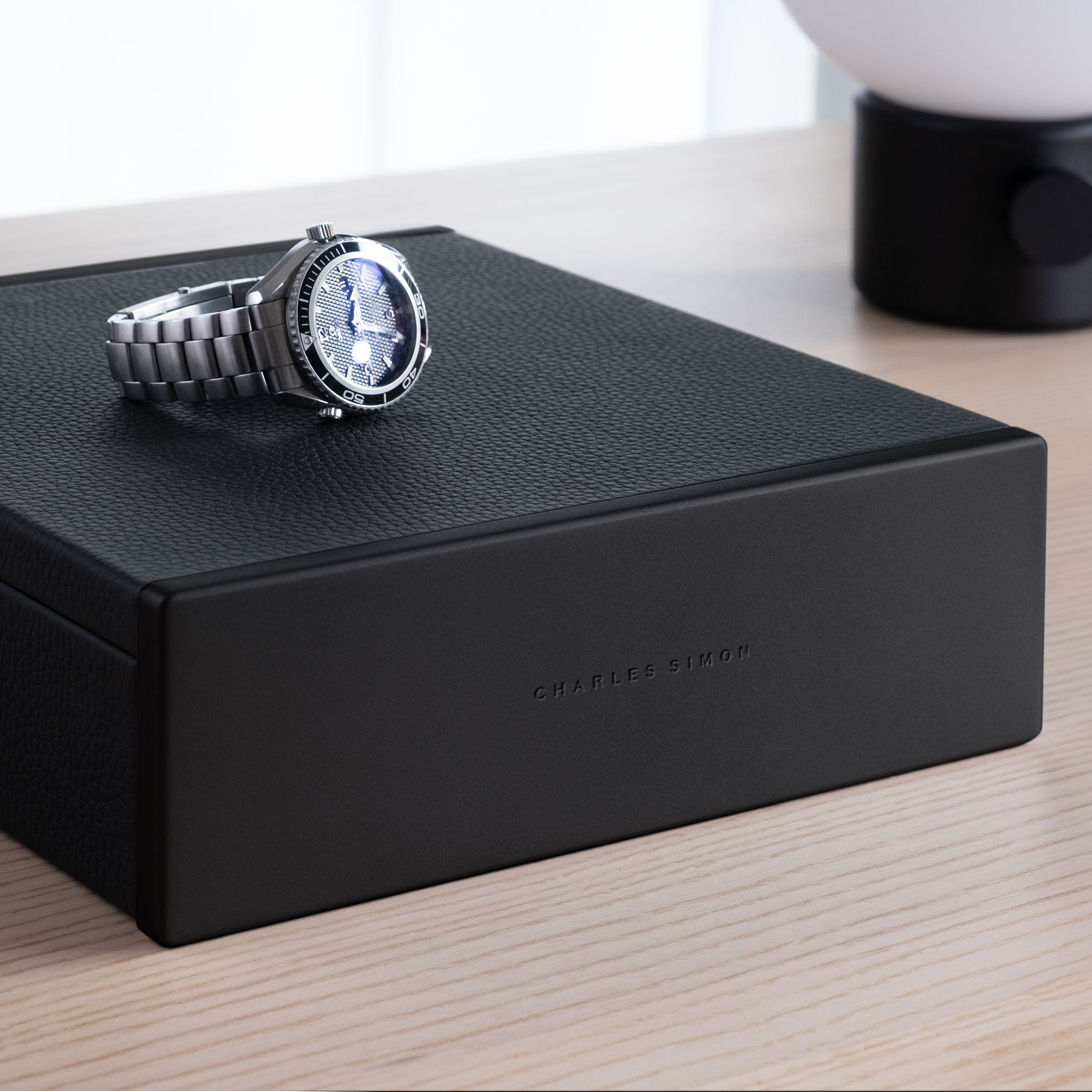 Luxury men's watch placed on top of all black Spence watch box in modern apartment