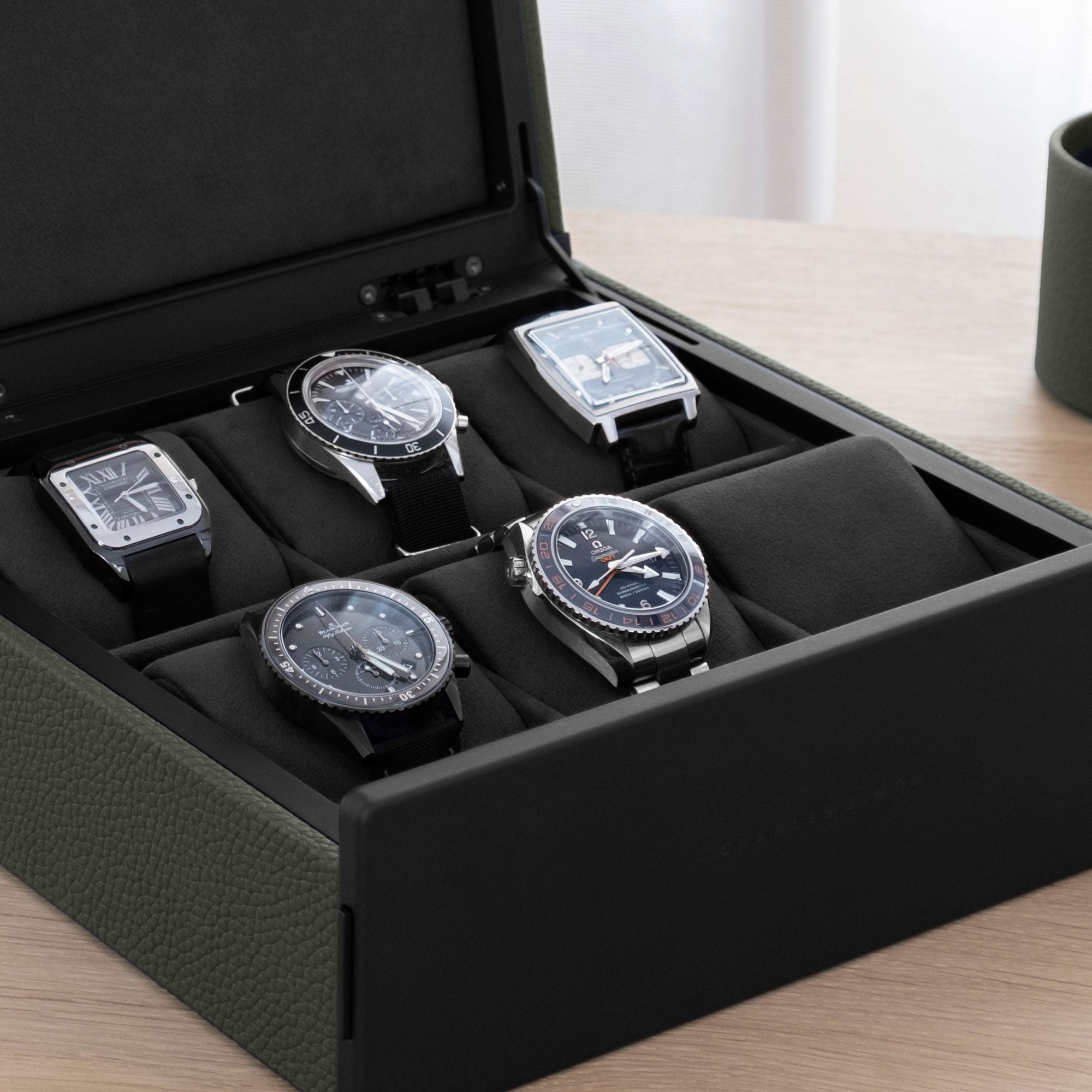 Lifestyle shot of Spence luxury watch box for 6 watches filled with men's watches including Jaeger Lecoultre, Blancpain and Omega placed on removable Alcantara cushions