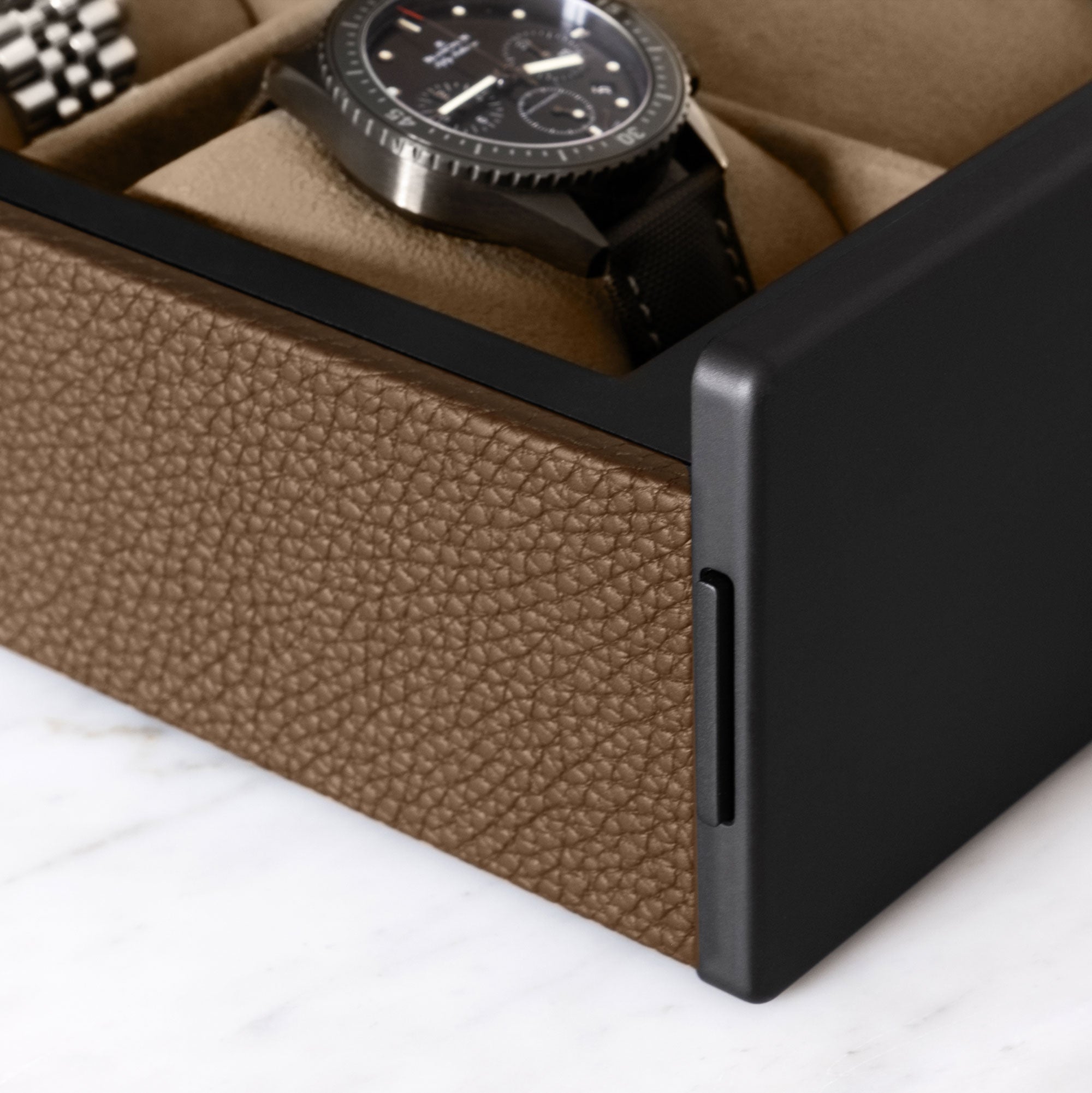 Detail shot of tan leather and black carbon fiber and anodized aluminum of the luxury watch box by Charles Simon