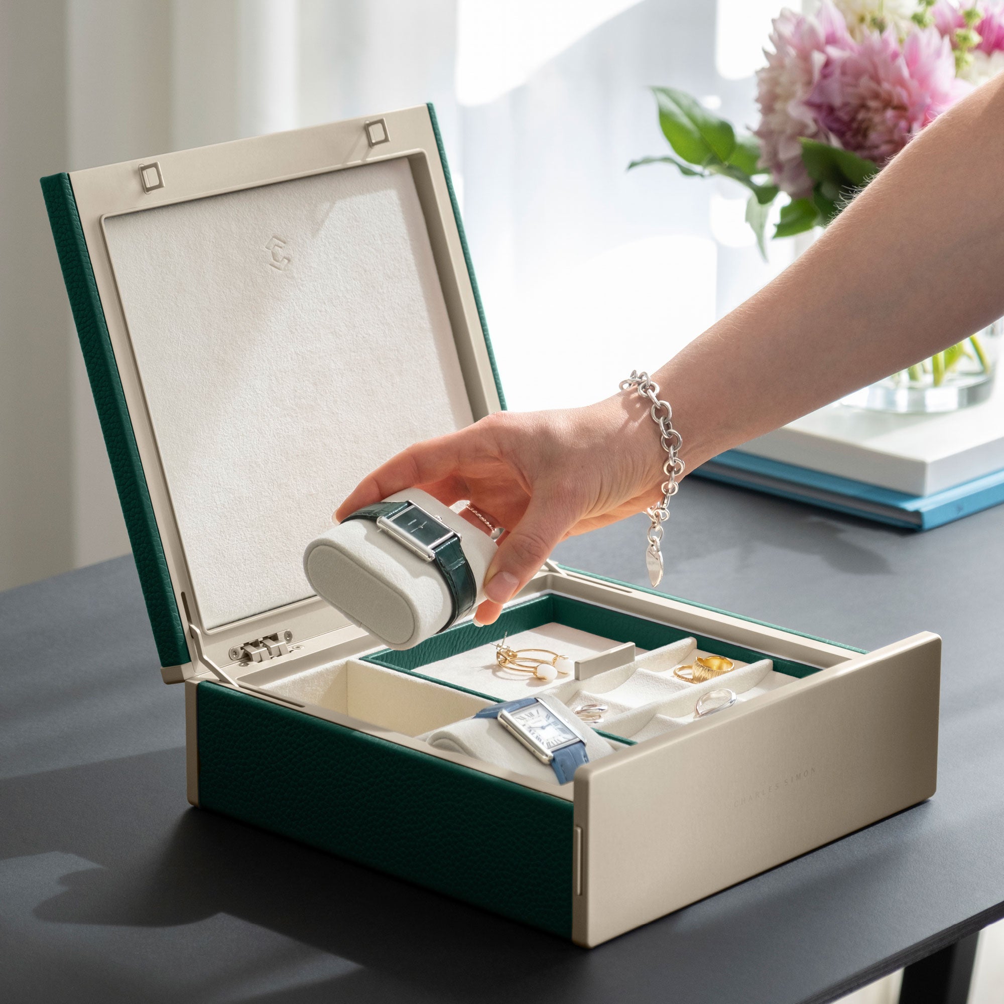 Woman taking her Cartier watch from her emerald leather gold watch and jewelry box featuring practical jewelry organization compartments. 