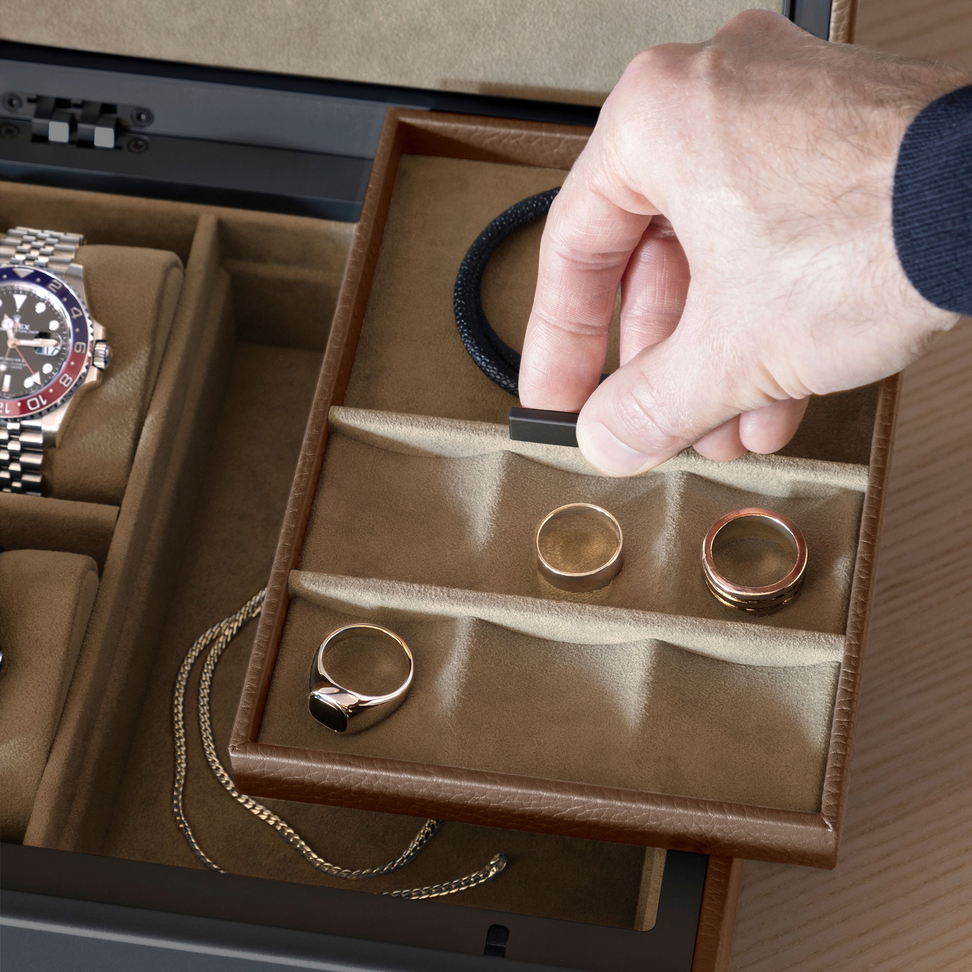 Detail photo of man lifting jewelry tray of the Taylor 2 Watch and Jewelry box in tan leather and camel interior. The Jewelry organizer is storing several rings, a necklace and a Rolex watch.